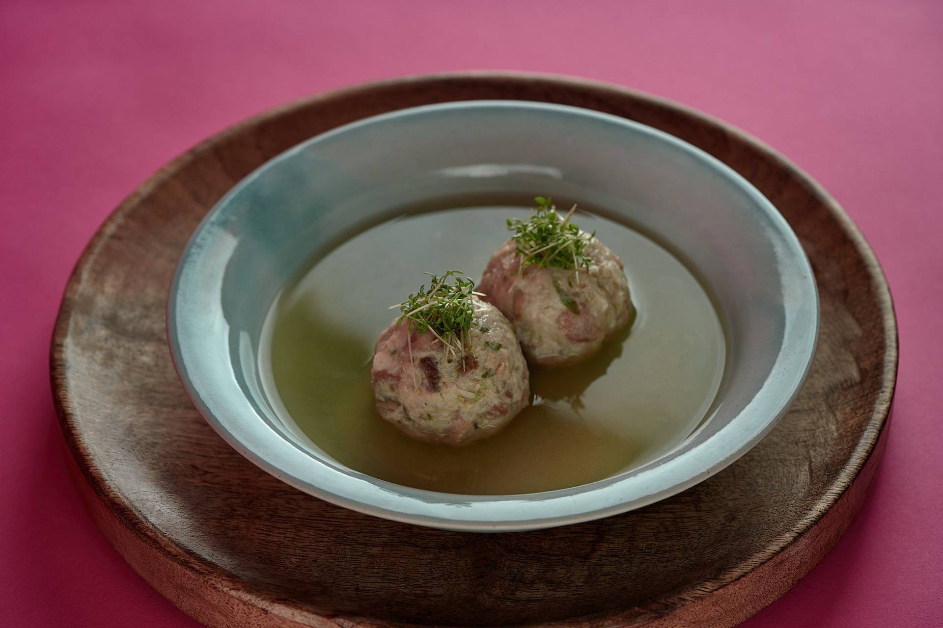 vegan-bread-dumplings-with-brussels-sprouts-and-vegetable-broth vegan bread dumplings with brussels sprouts and vegetable broth on a turquoise plate with pink background