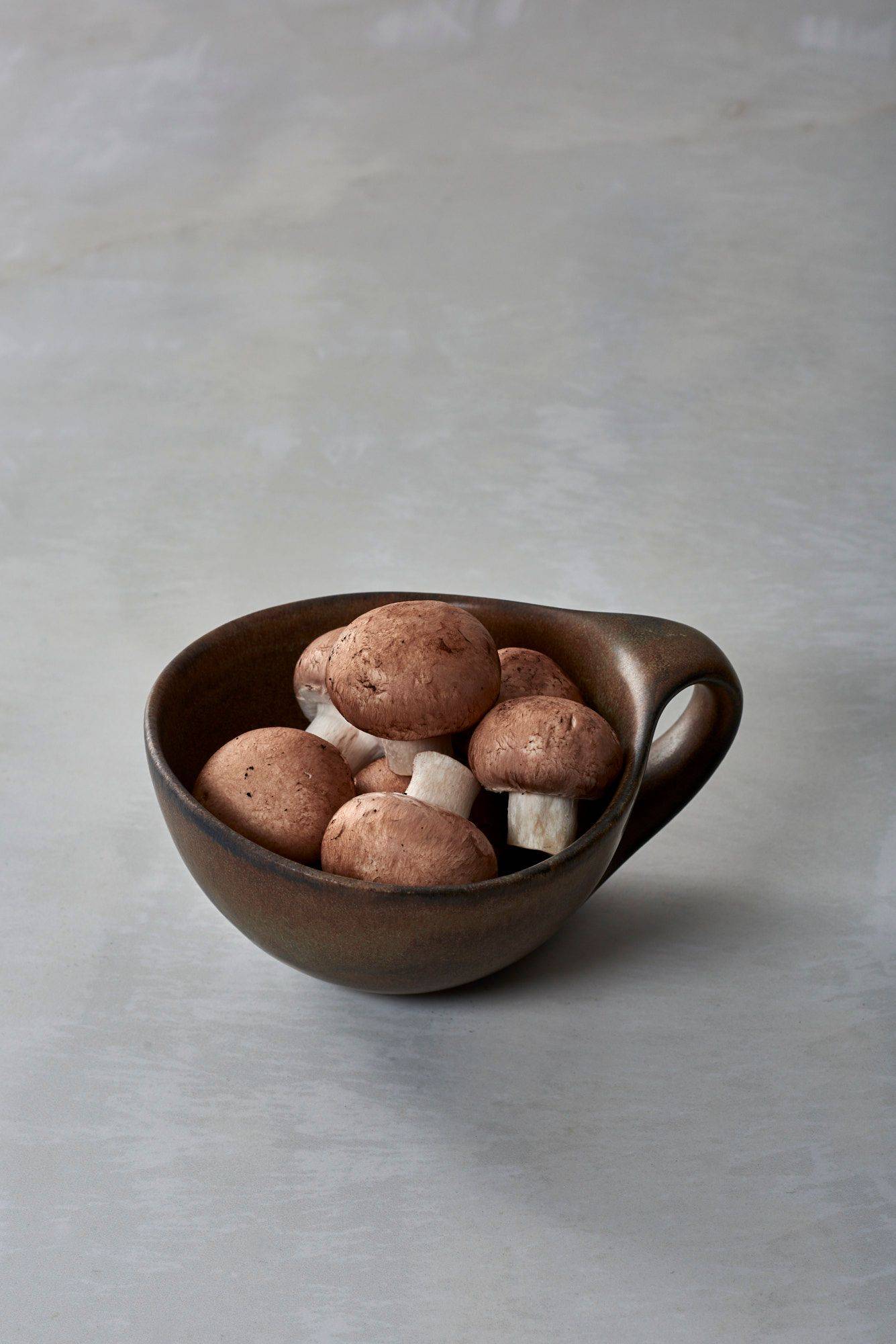mushrooms mushrooms in a brown ceramic cup with white sapienstone top