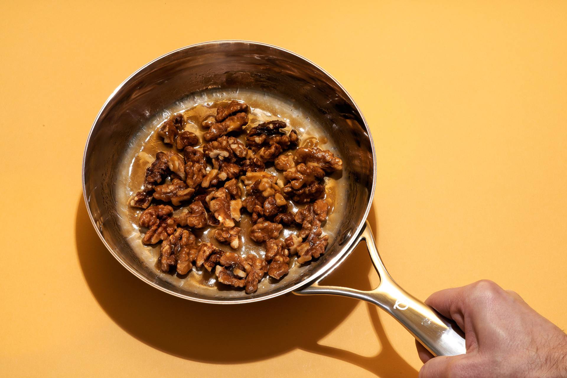 candied-walnuts an olav pan with candied walnuts on yellow background