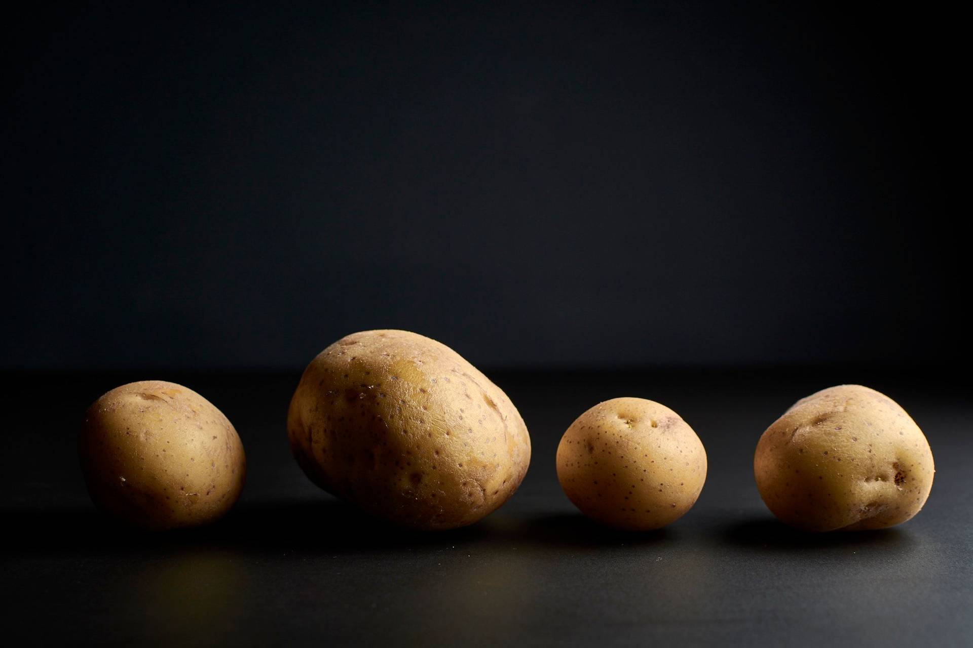 potatoes four potatoes in a row on black background
