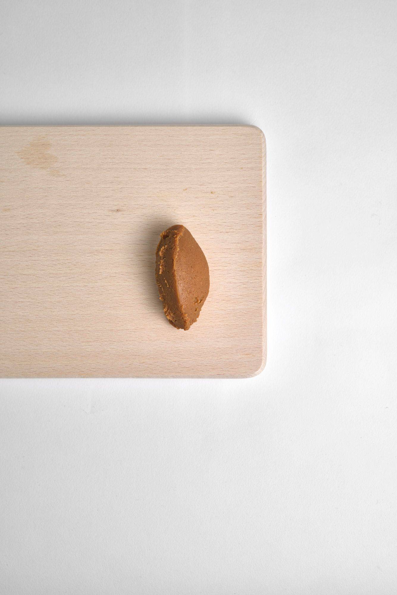 miso a spoon of miso paste on a wooden board on white background