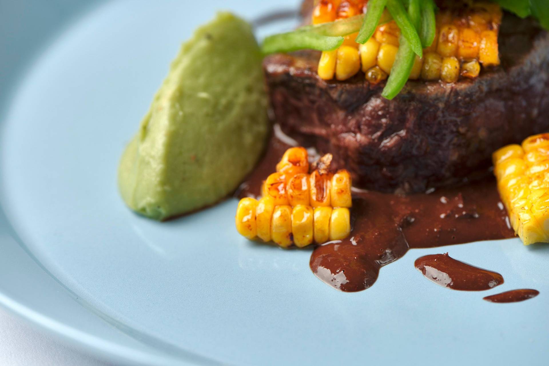 beef-steak-with-dark-beer-mole-sauce-corn-and-guacamole beef steak with dark beer mole sauce corn and guacamole on a blue plate