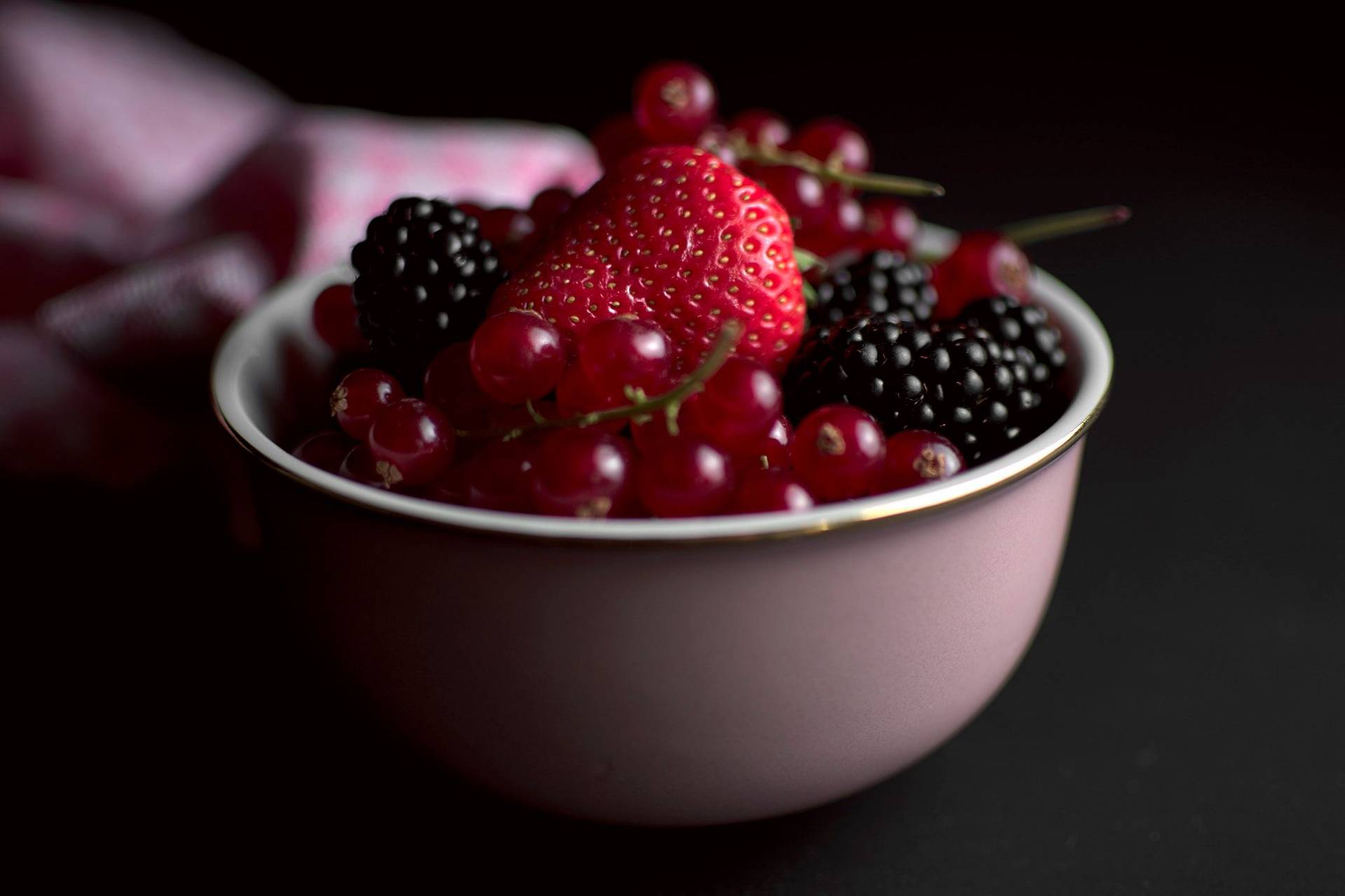 berries a pink bowl of mixed berries with black background