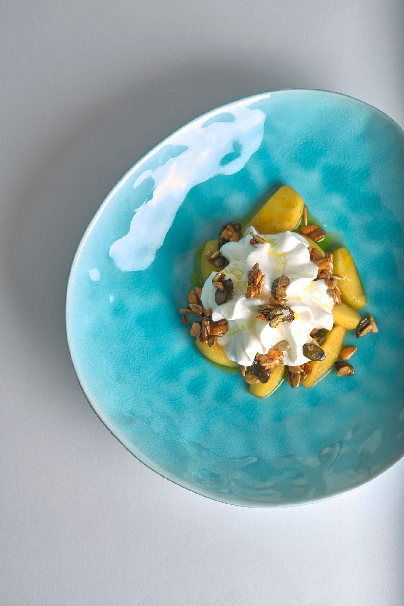 caramelized-apples-with-nuts-quark-and-linseed-oil caramelized apples with nuts quark and linseed oil on a turquoise plate with white background