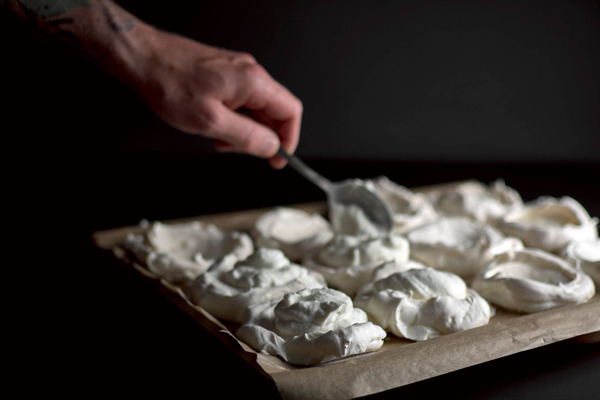 filling pavlova meringue shells filling pavlova meringue shells on a baking sheet with black background