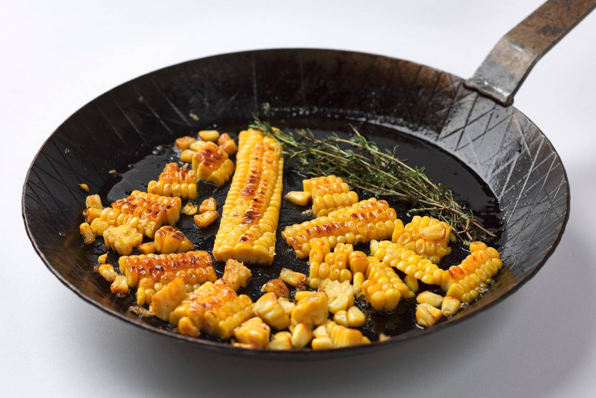 roasted-corn roasted corn in a cast iron pan with white background