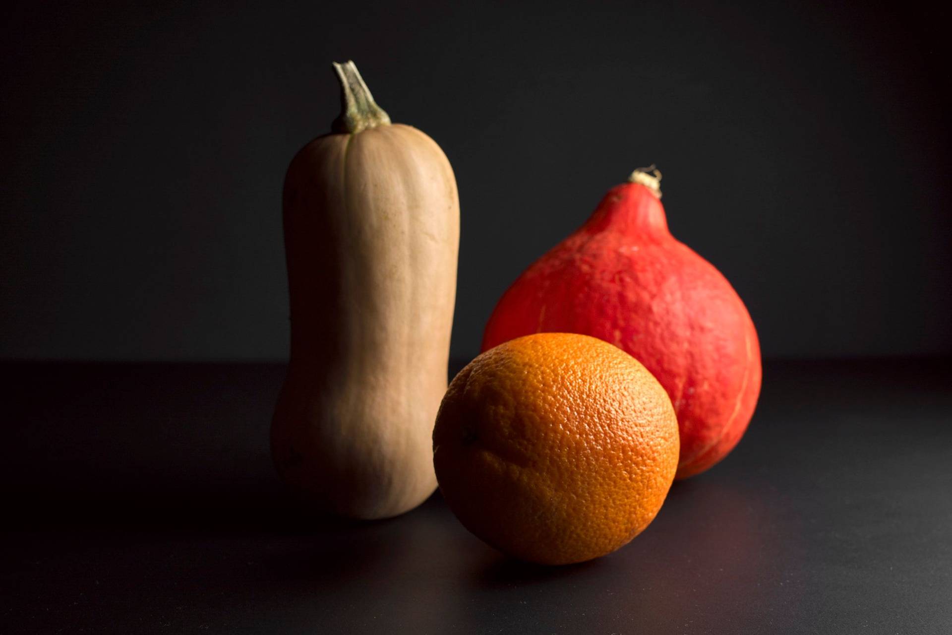 kuerbis-und-orange zwei sorten kürbis und eine orange mit schwarzem hintergrund