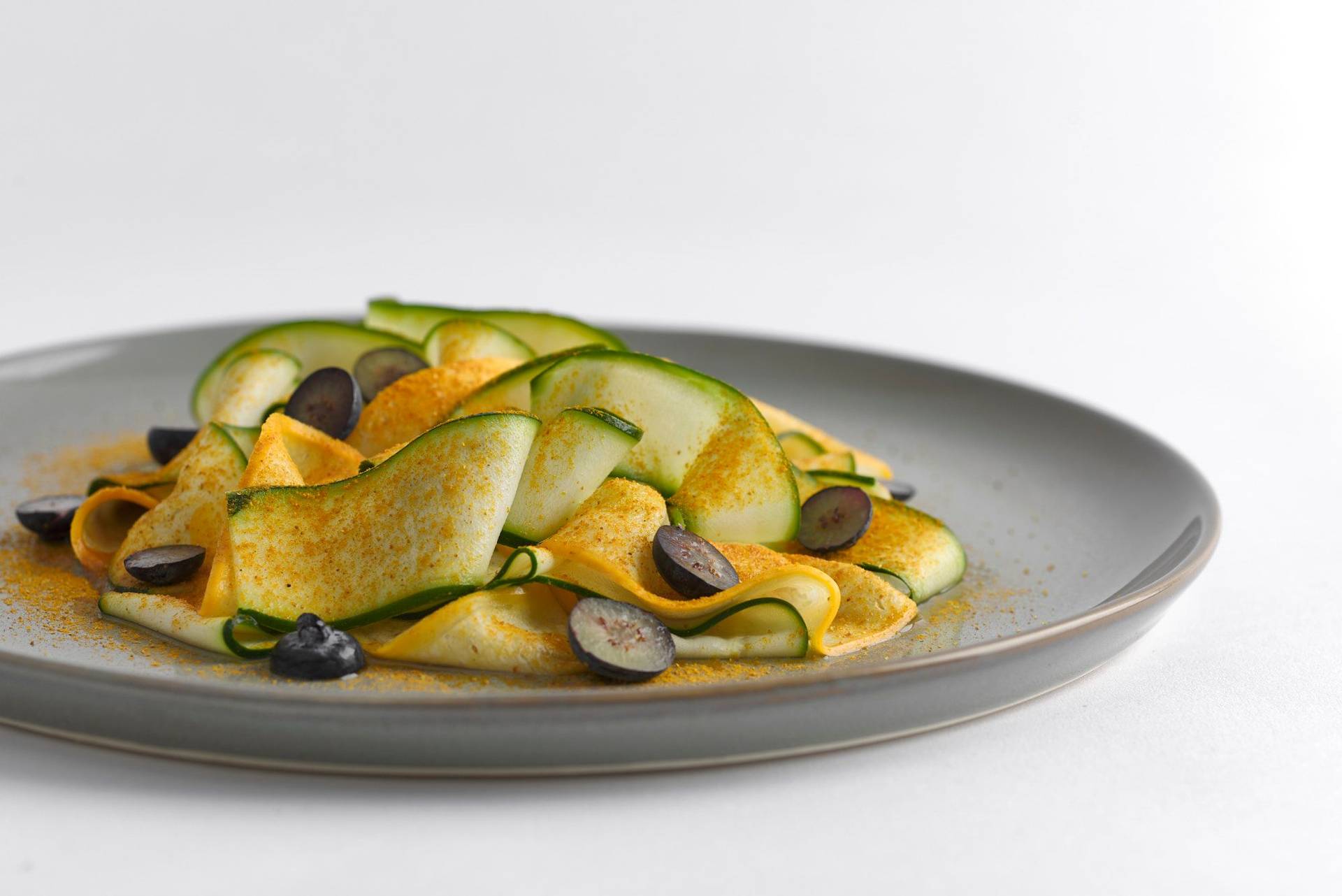 courgette-with-almond-butter-madras-curry-and-blueberries courgette with almond butter madras curry and blueberries on a gray plate with white background