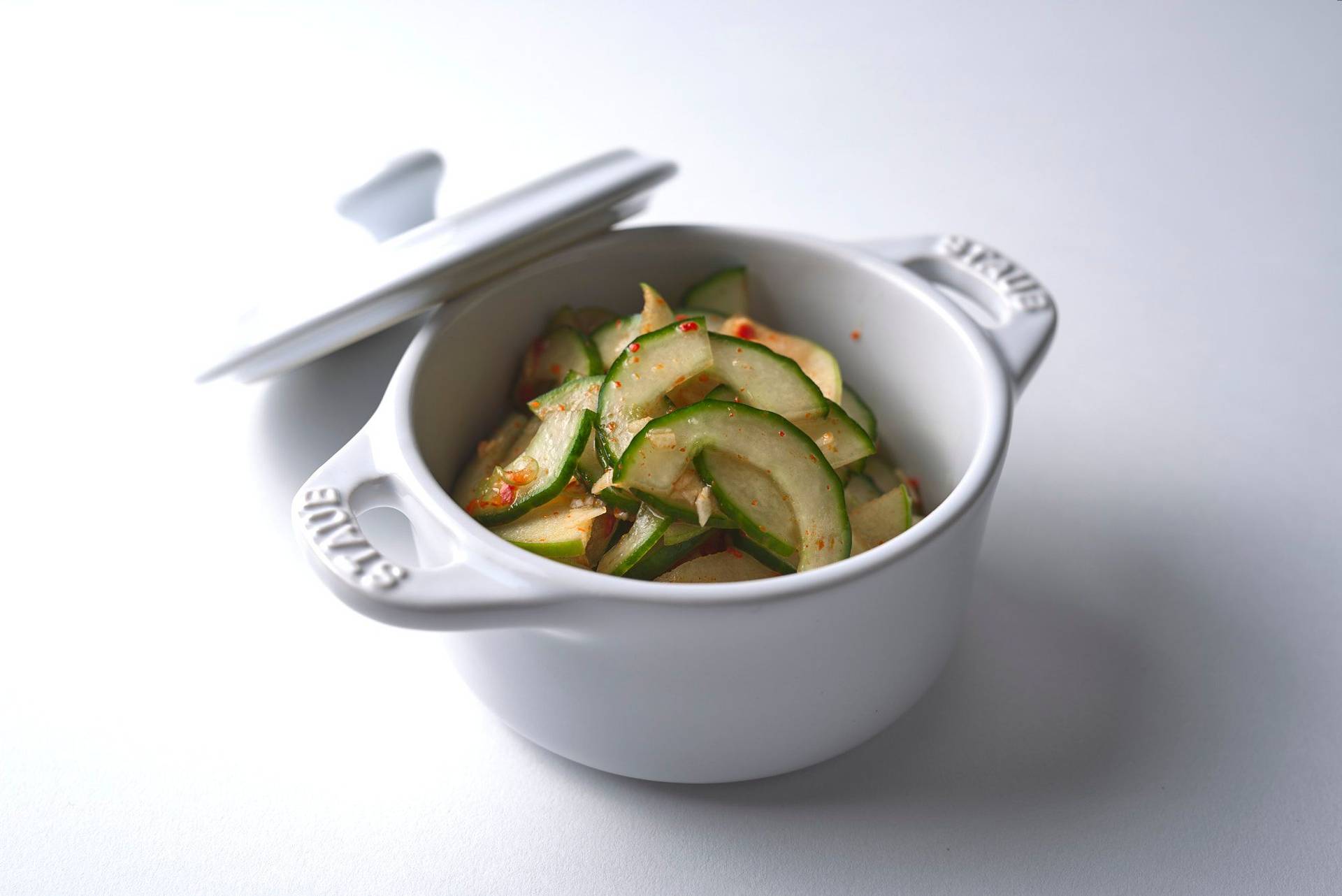 cucumber-kimchi fast cucumber kimchi in a white staub pot with white background