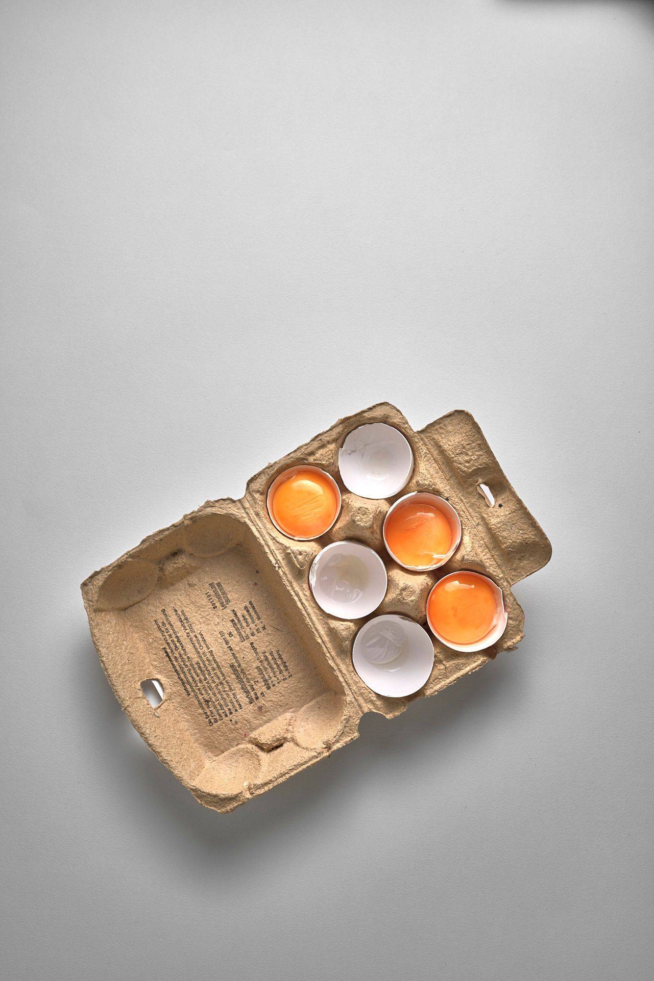 eggs cracked eggs in egg shells with a box on white background