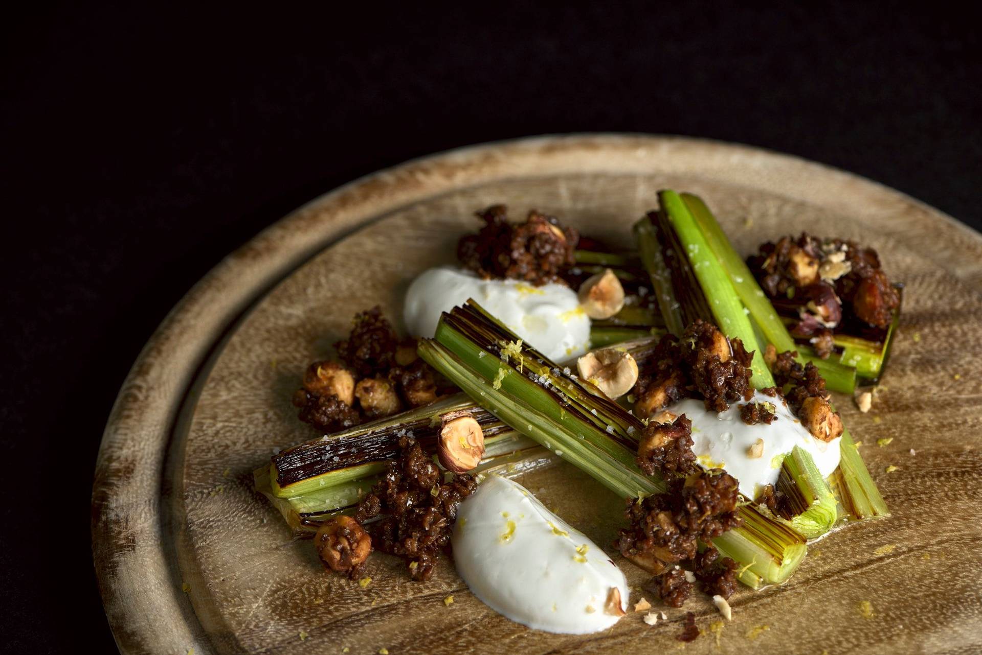 beer-braised-leek-with-pumpernickel-and-skyr beer braised leek with pumpernickel and skyr on a wooden board with black background