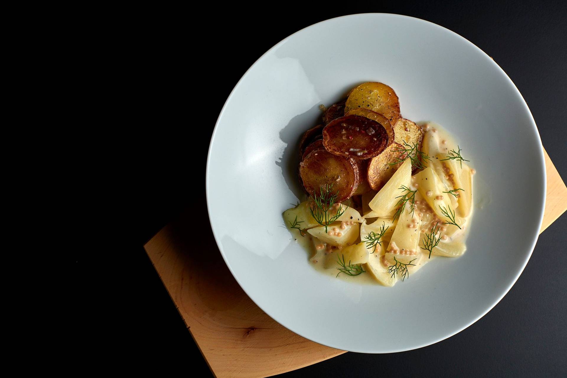 braised-cucumbers-with-roasted-potatoes braised cucumbers with roasted potatoes in a white bowl on black background