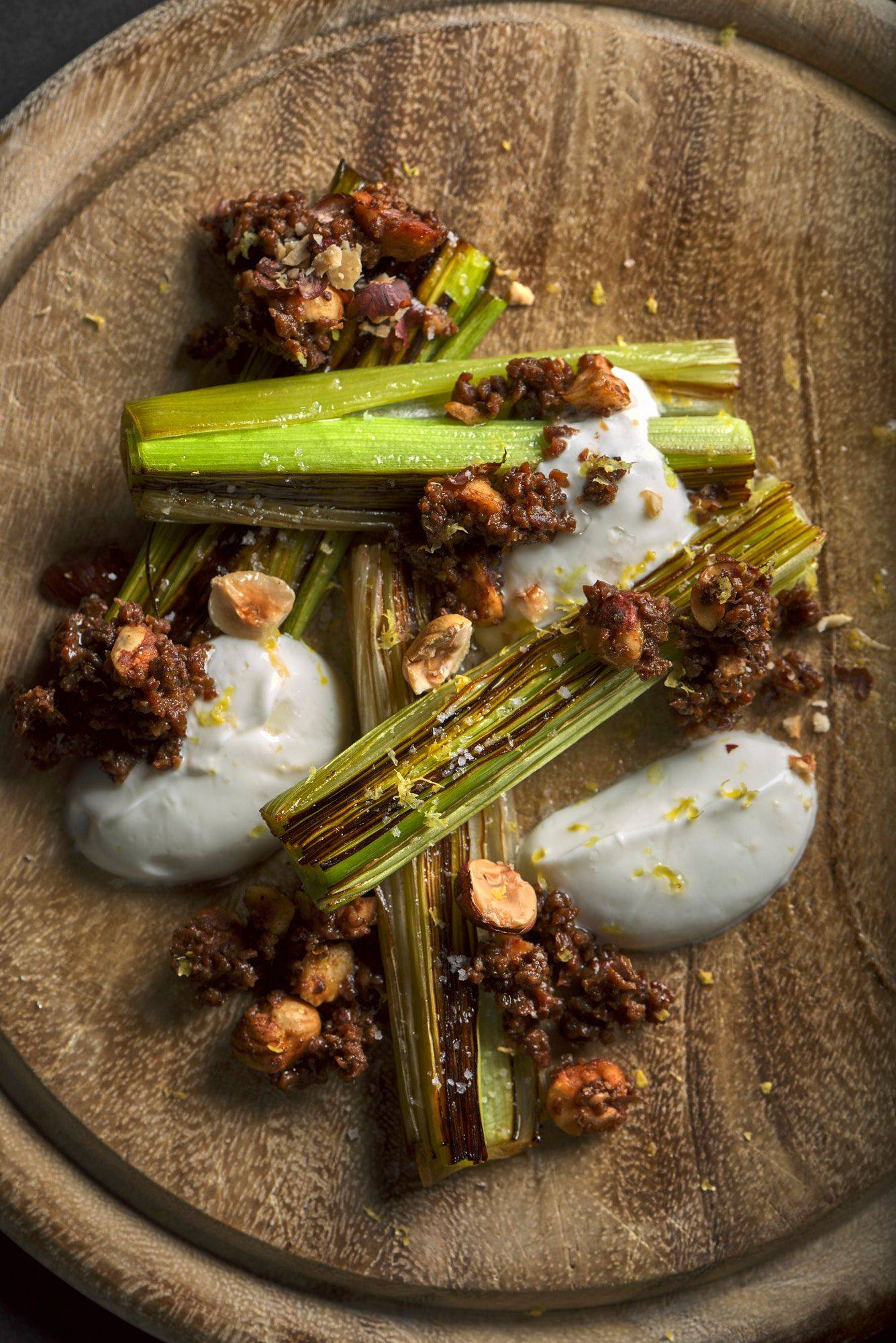 beer-braised-leek-with-pumpernickel-and-skyr beer braised leek with pumpernickel and skyr on a wooden board with black background