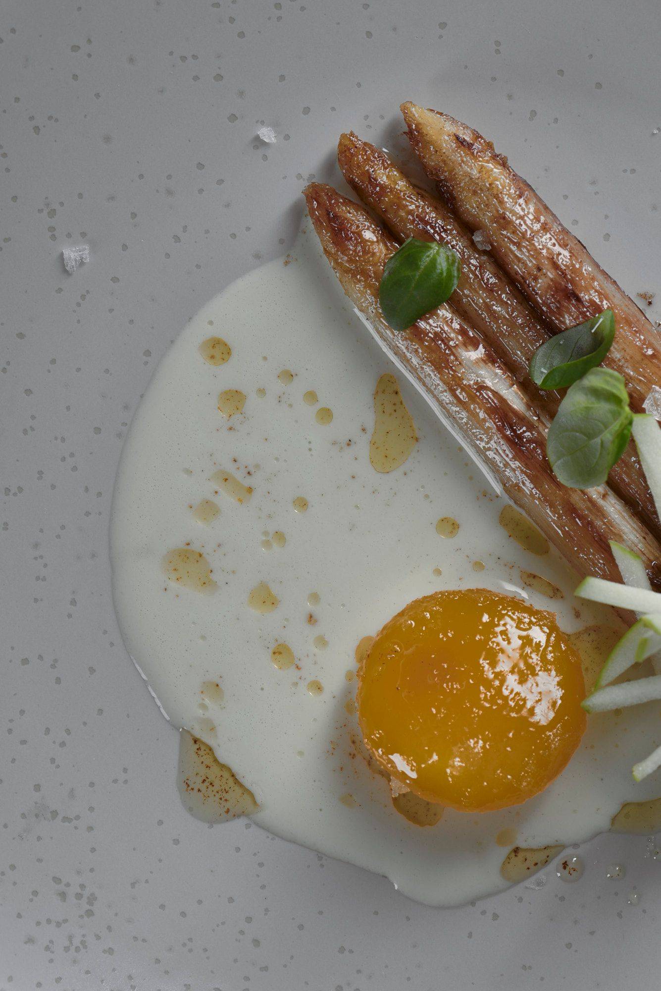 roasted-white-asparagus-with-cured-egg-yolk-basil-and-green-apple roasted white asparagus with cured egg yolk basil and green apple on a beige plate