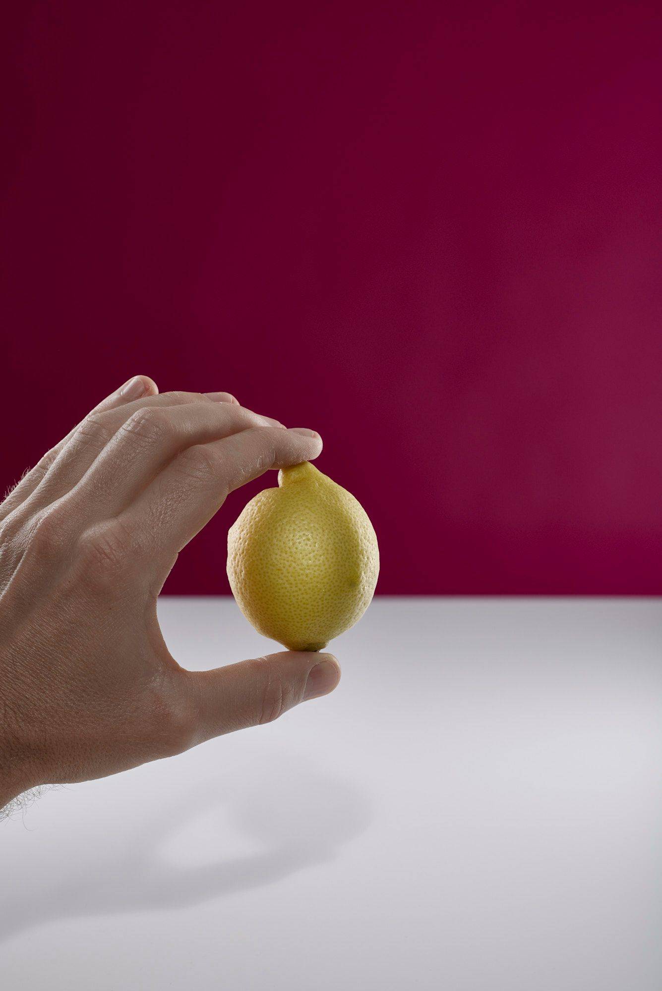 lemon hand holding a lemon with white and pink background