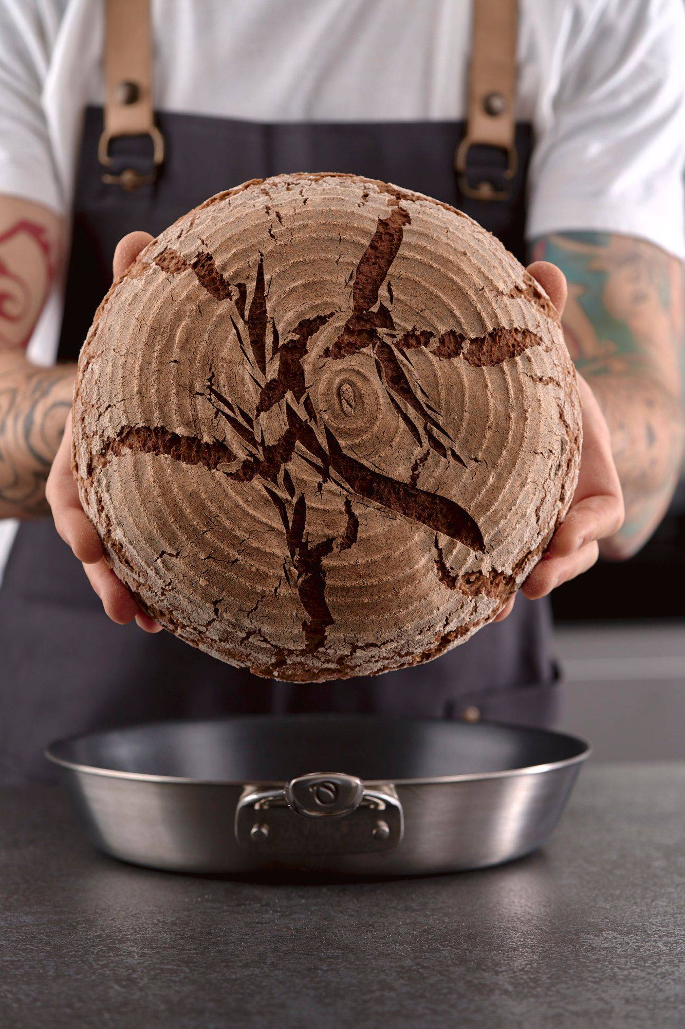 pan-baked-rye-sourdough-bread man holds a pan baked rye sourdough bread in home kitchen