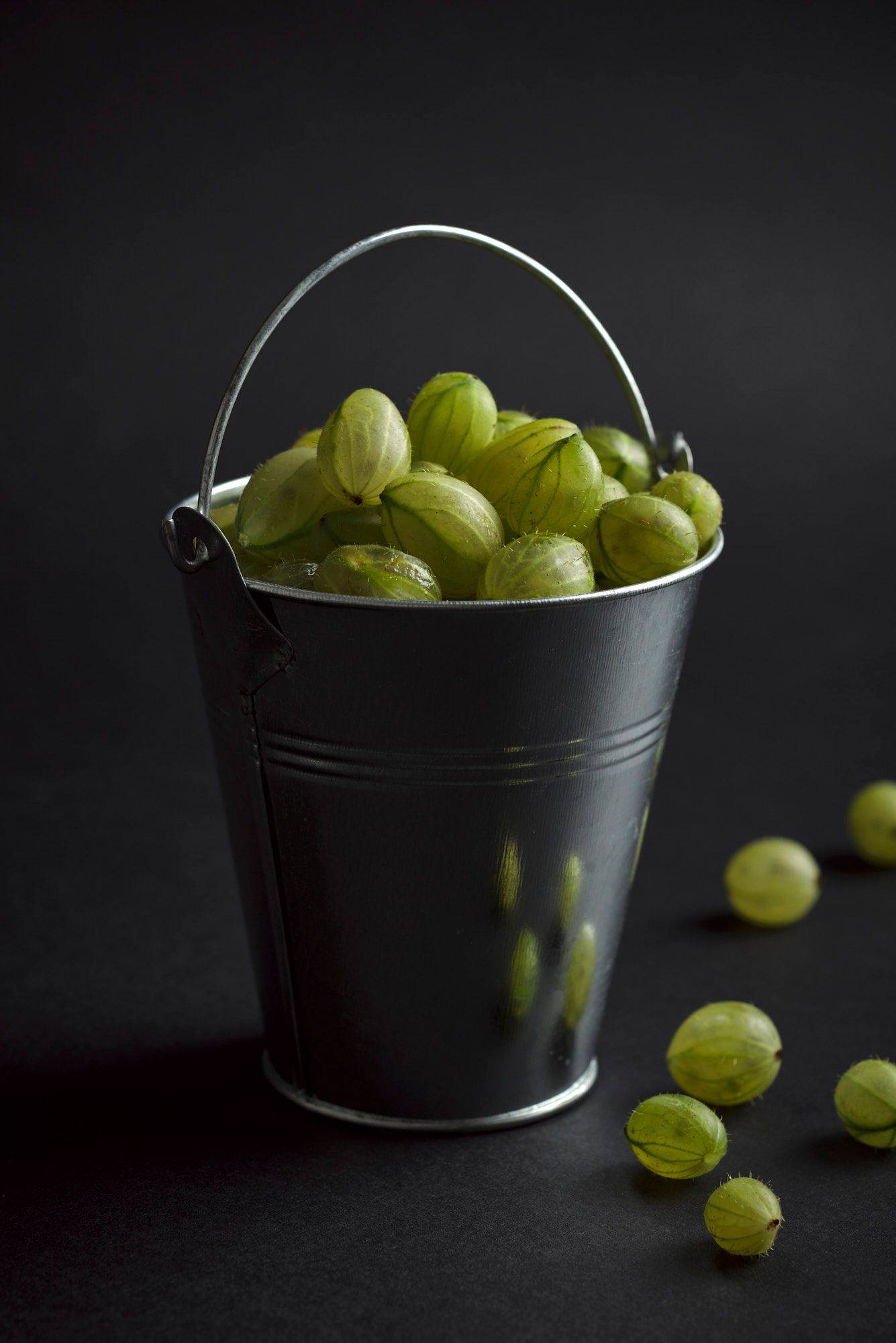 gooseberries a mini bucket with gooseberriescod ceviche with gooseberries in a turquoise ceramic bowl with black background