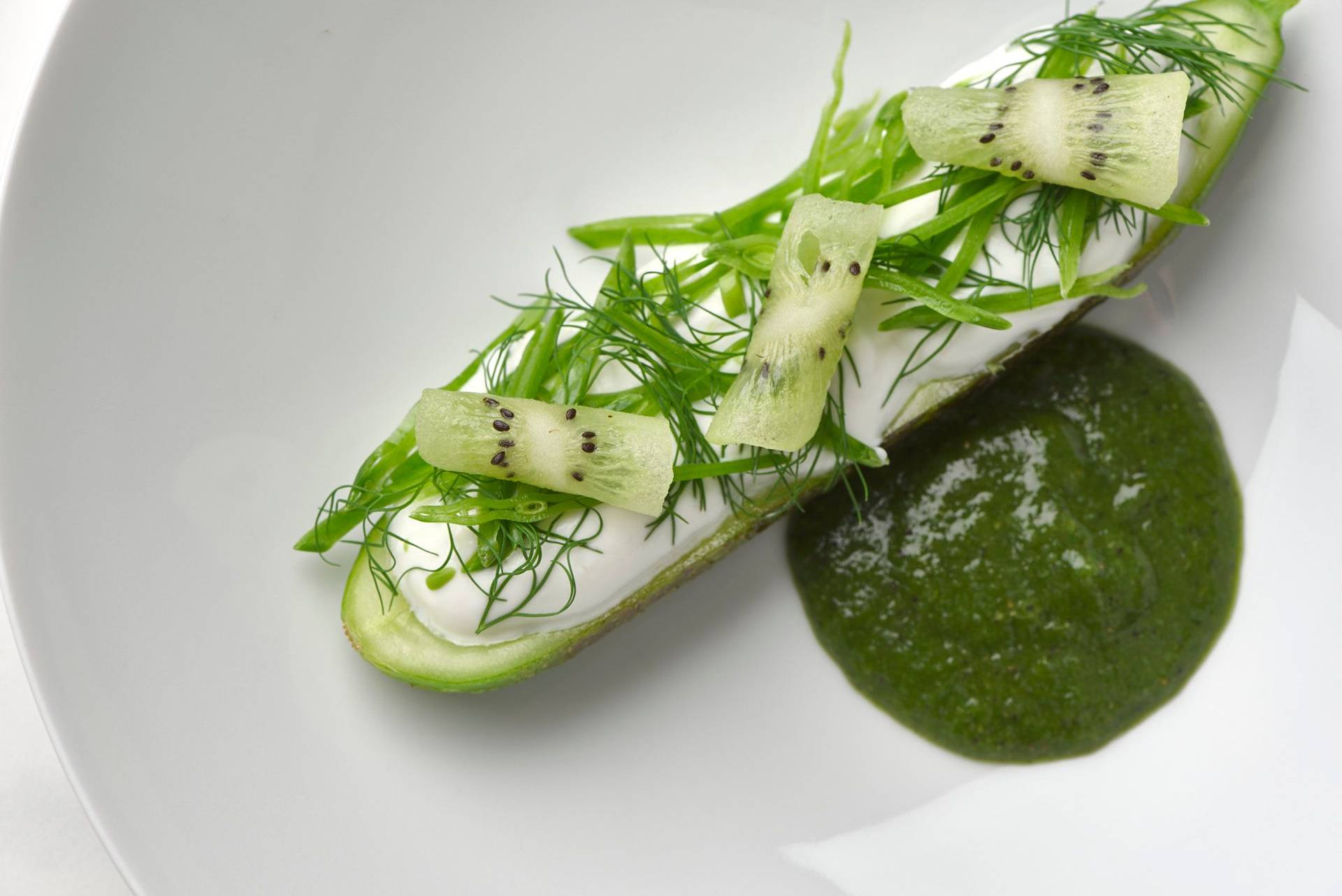 charred-cucumber-with-kiwi-salsa-skyr-and-dill charred cucumber with kiwi salsa skyr and dill on a white plate with a marbled sapienstone top