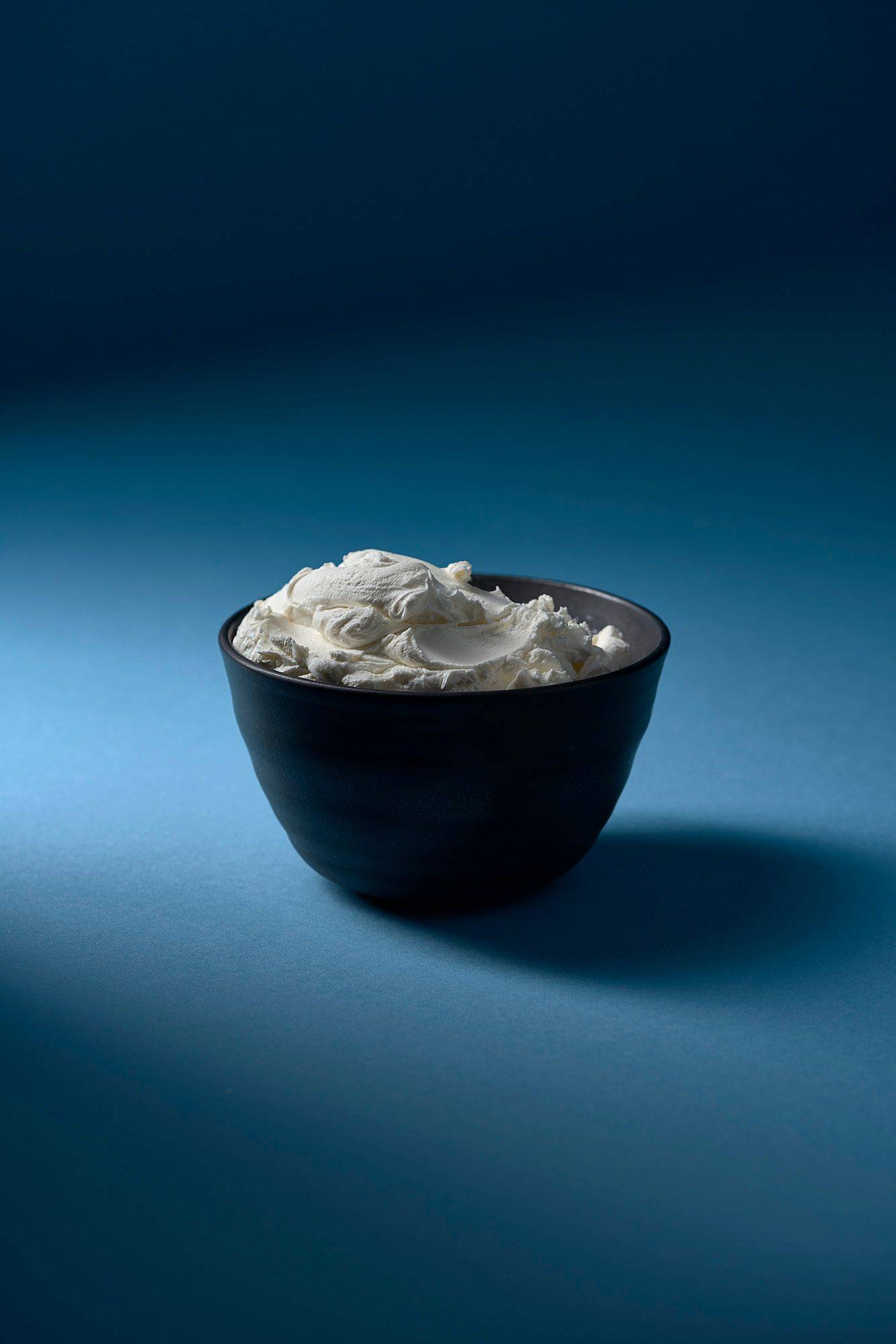 mascarpone-kaese mascarpone käse in grauer keramik schale mit blauem hintergrund