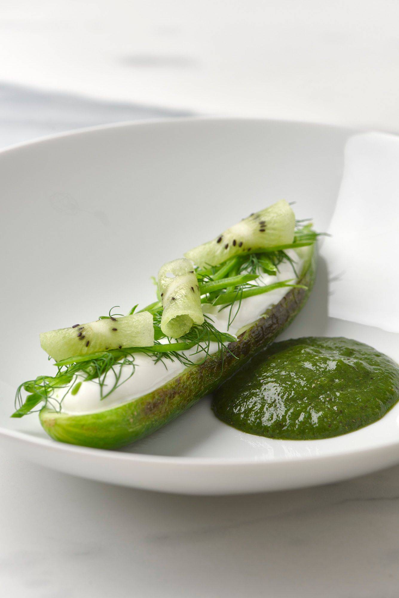 charred-cucumber-with-kiwi-salsa-skyr-and-dill charred cucumber with kiwi salsa skyr and dill on a white plate with a marbled sapienstone top