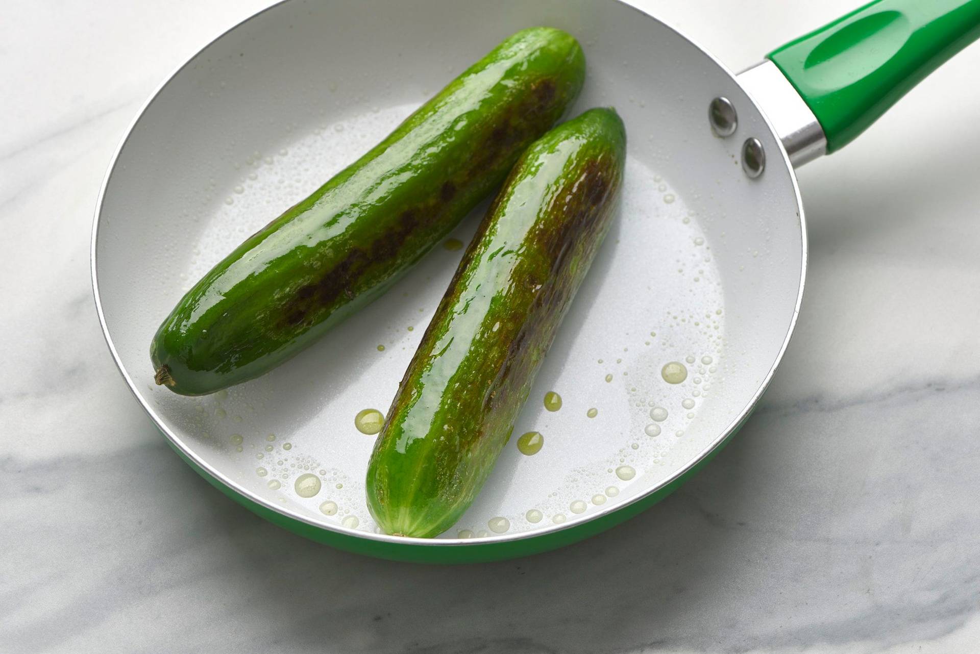 charred-cucumber two charred cucumbers in a green pan with a marbled sapienstone top