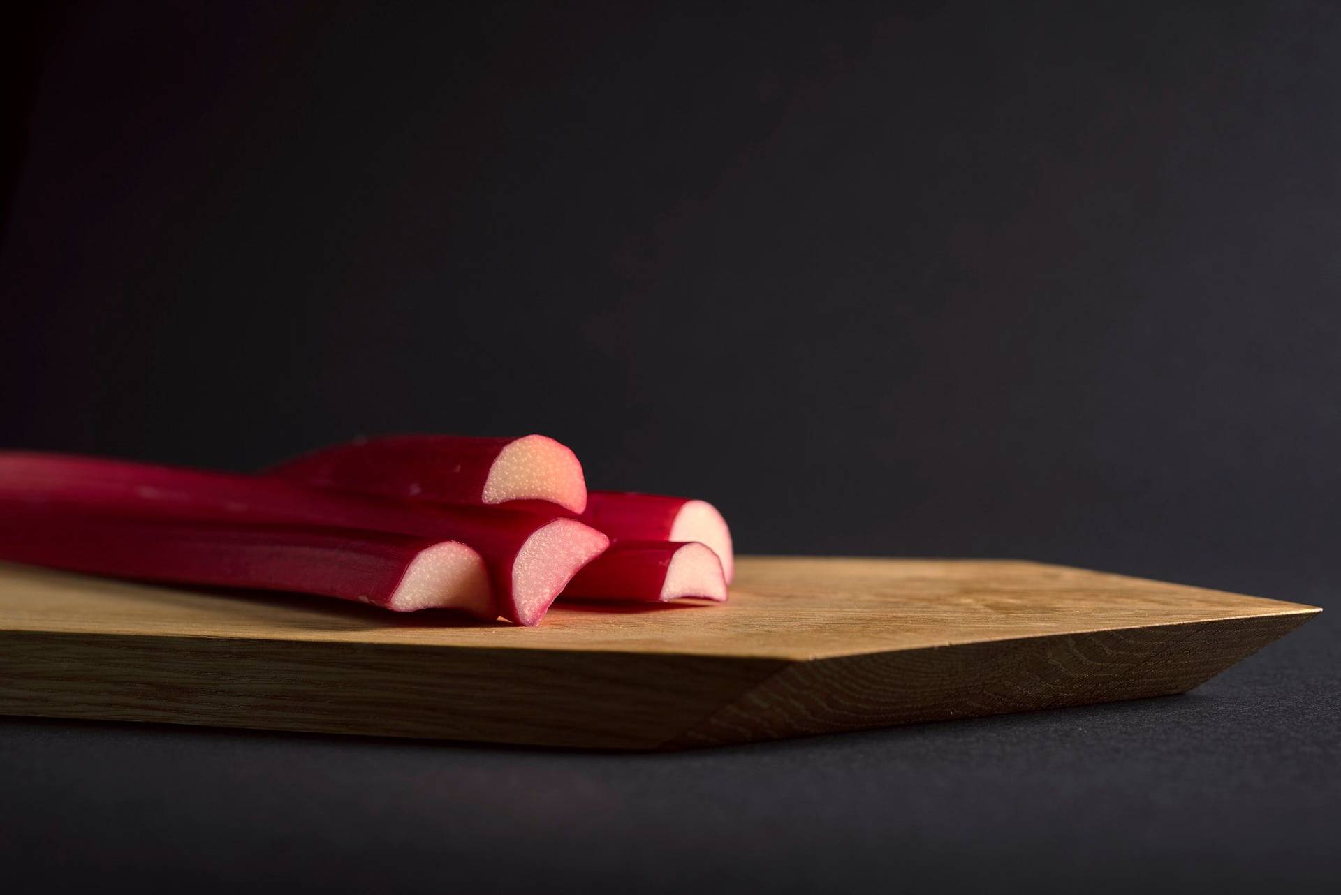 rhubarb three pieces of rhubarb on a wooden board with black background