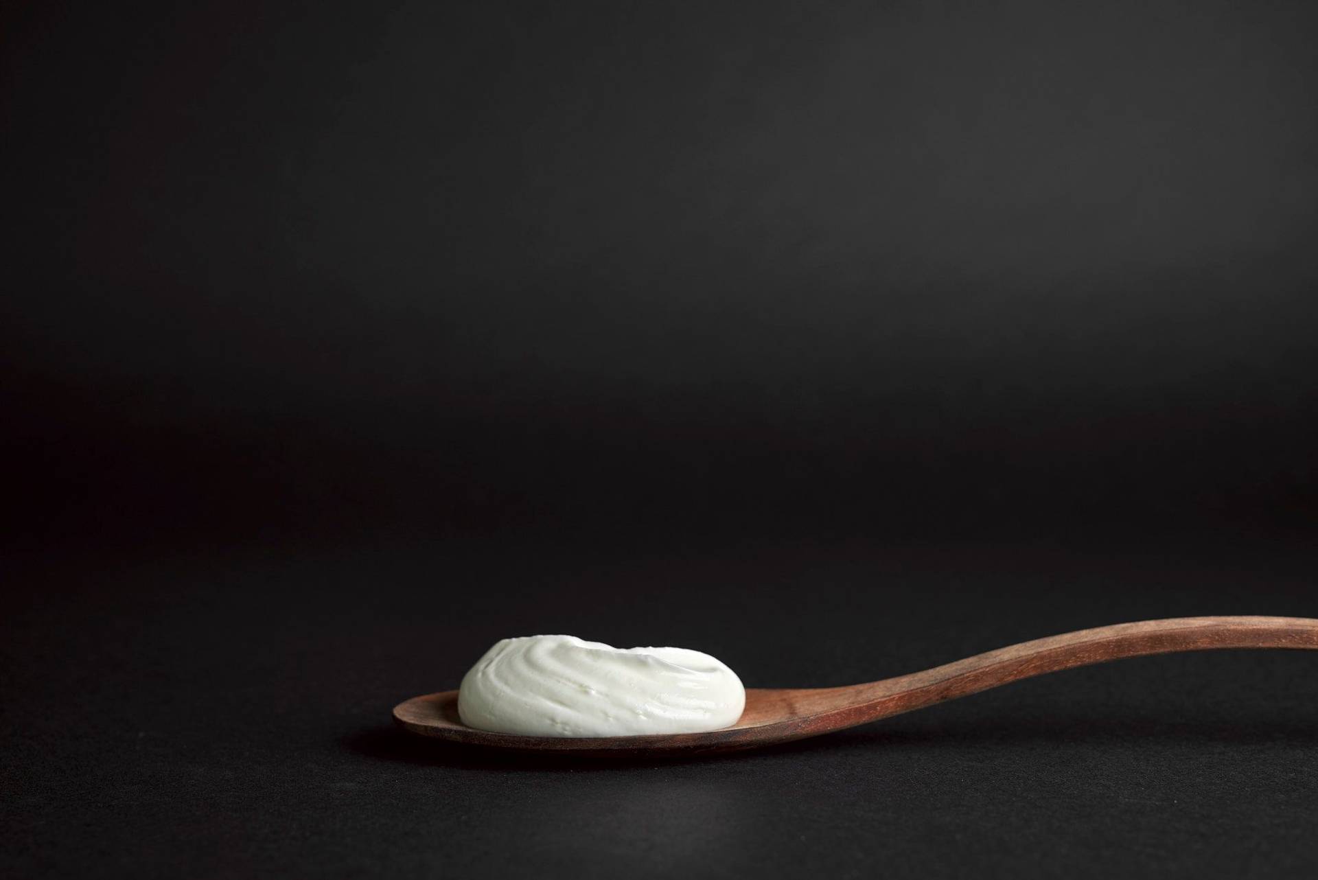 skyr a wooden spoon with skyr with black background