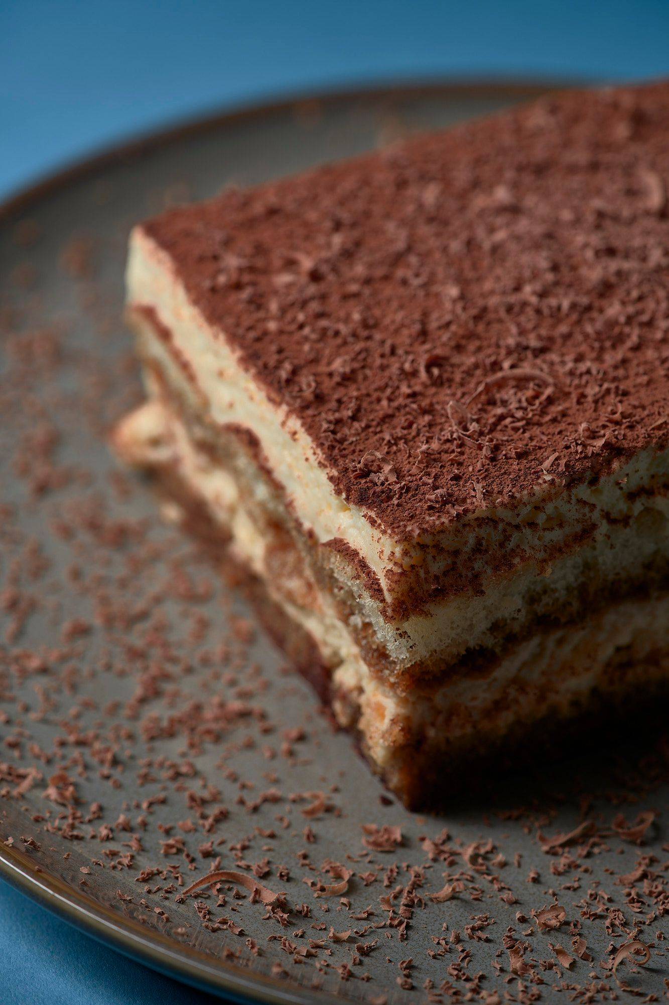 original-italienisches-tiramisu-dessert original italienisches tiramisu dessert auf grauem teller mit blauem hintergrund