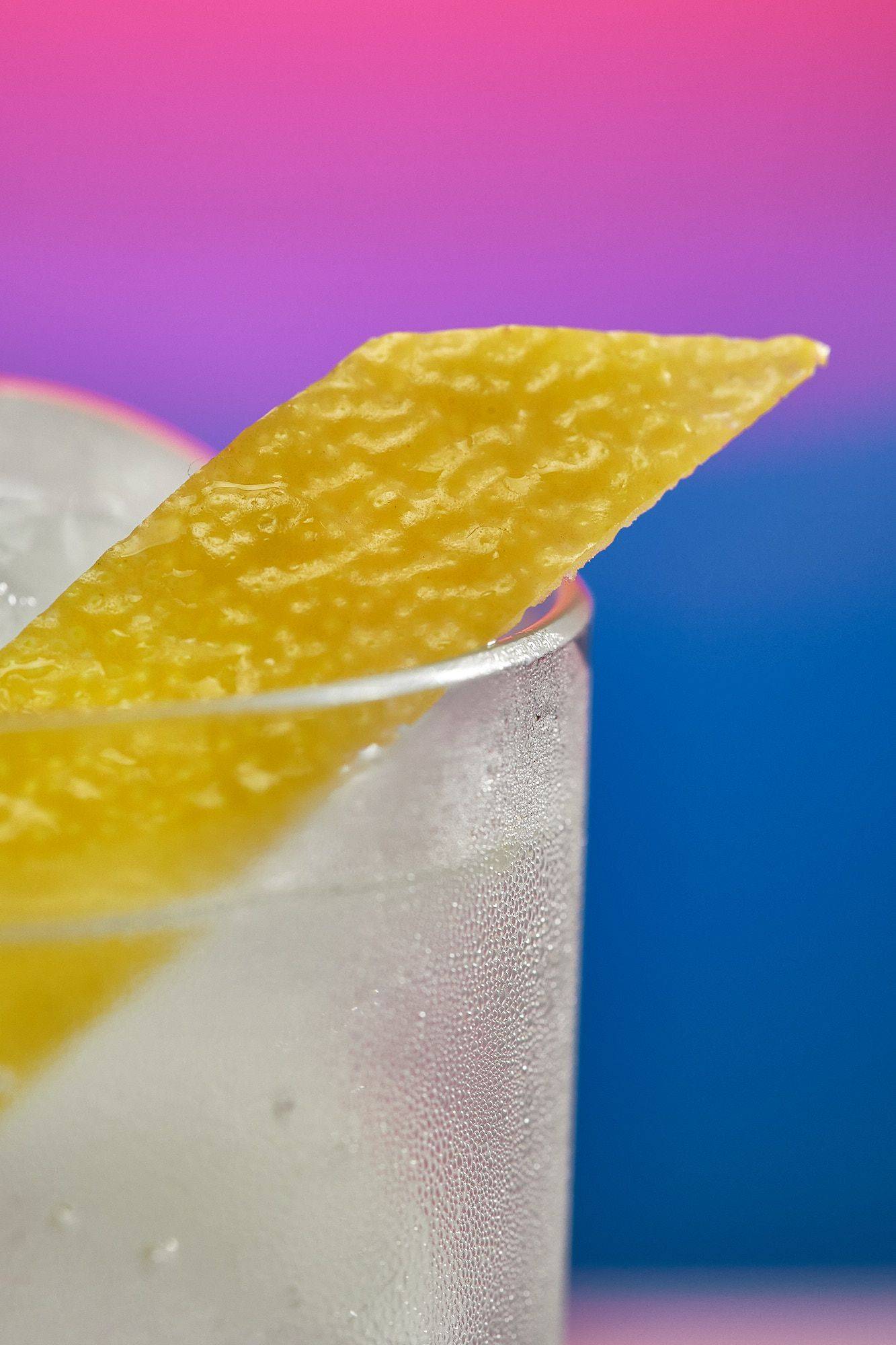 spicy-ginger-lemon-mocktails a glass of spicy ginger lemon mocktail on rainbow colored background