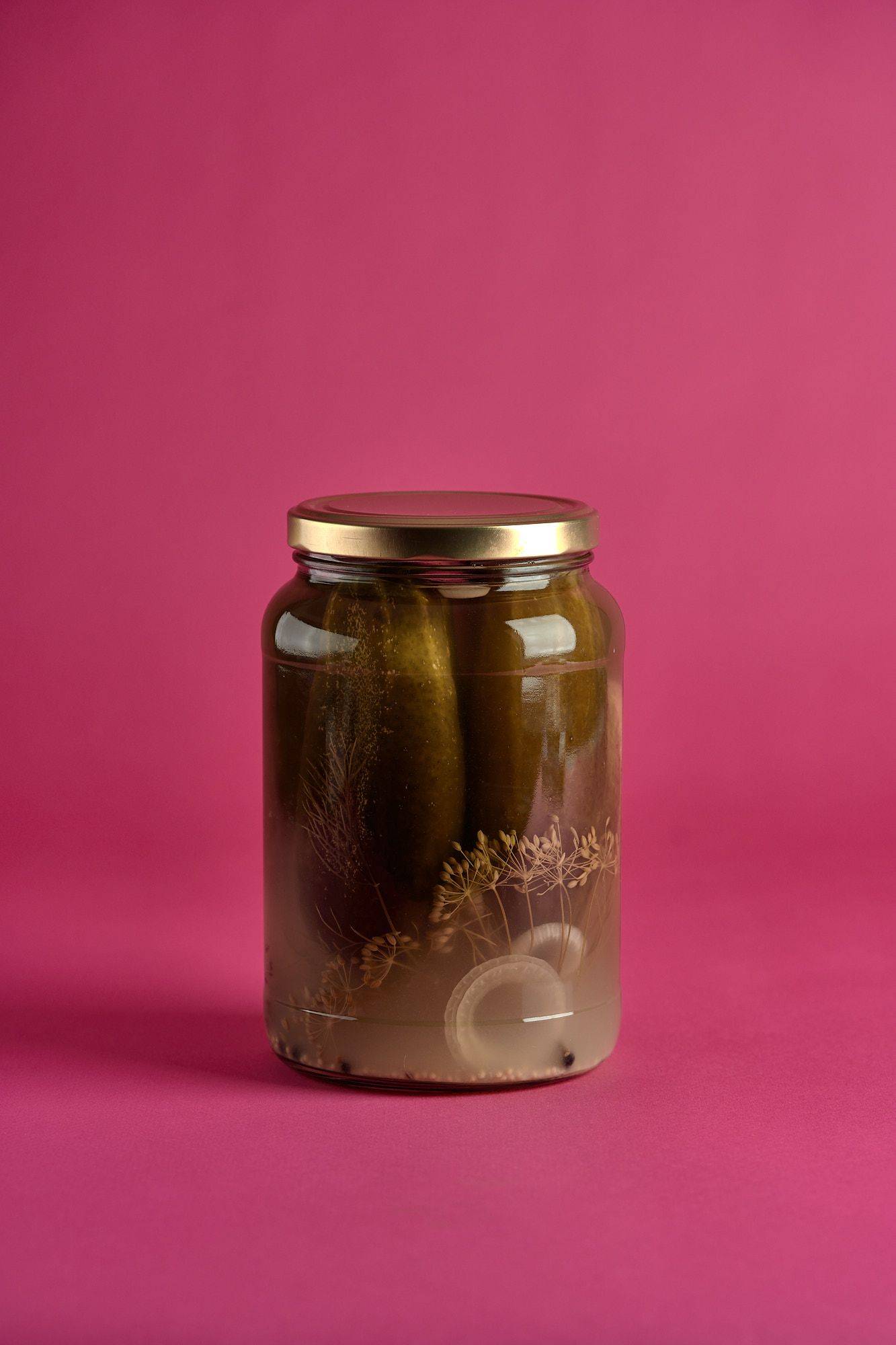 cucumber-pickles a jar of cucumber pickles on pink background