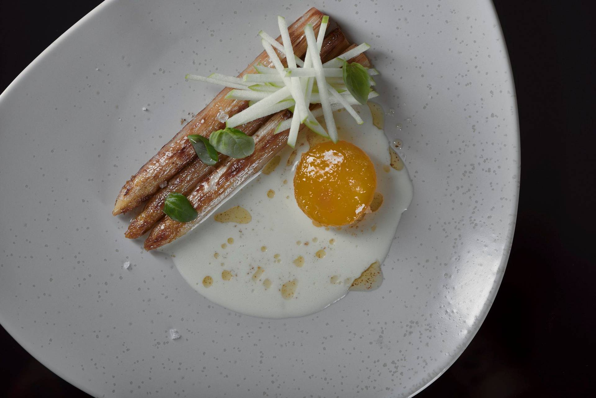 roasted-white-asparagus-with-cured-egg-yolk-basil-and-green-apple roasted white asparagus with cured egg yolk basil and green apple on a beige plate with black background