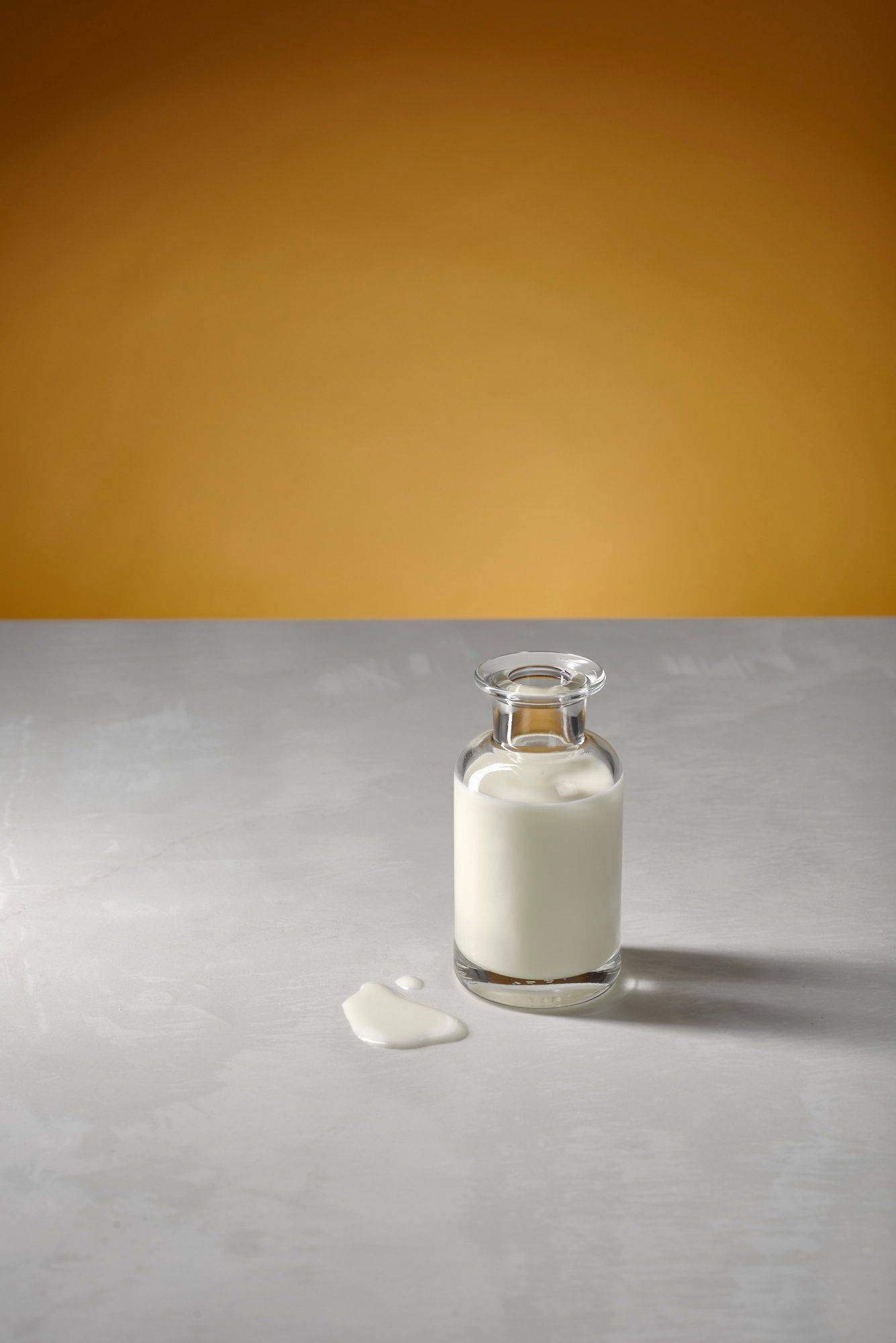 cream cream in a glass bottle with white sapienstone top and yellow background
