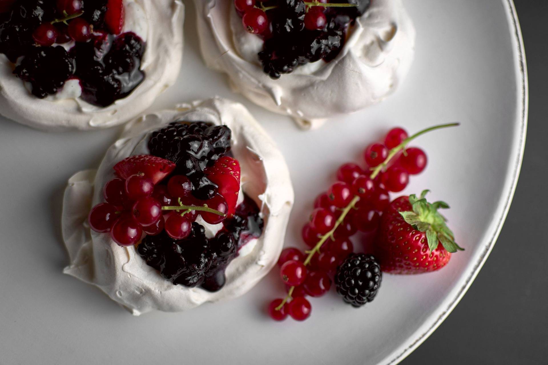 pavlova-with-berries-and-salted-cream pavlova with berries and salted cream on a white plate with black background