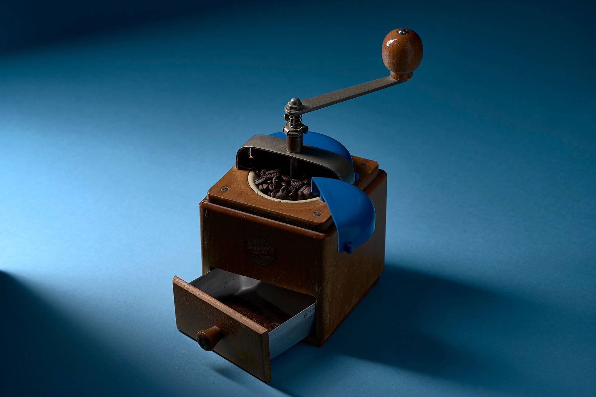 kaffee frisch gemahlener kaffee in einer vintage kaffeemühle mit blauem hintergrund