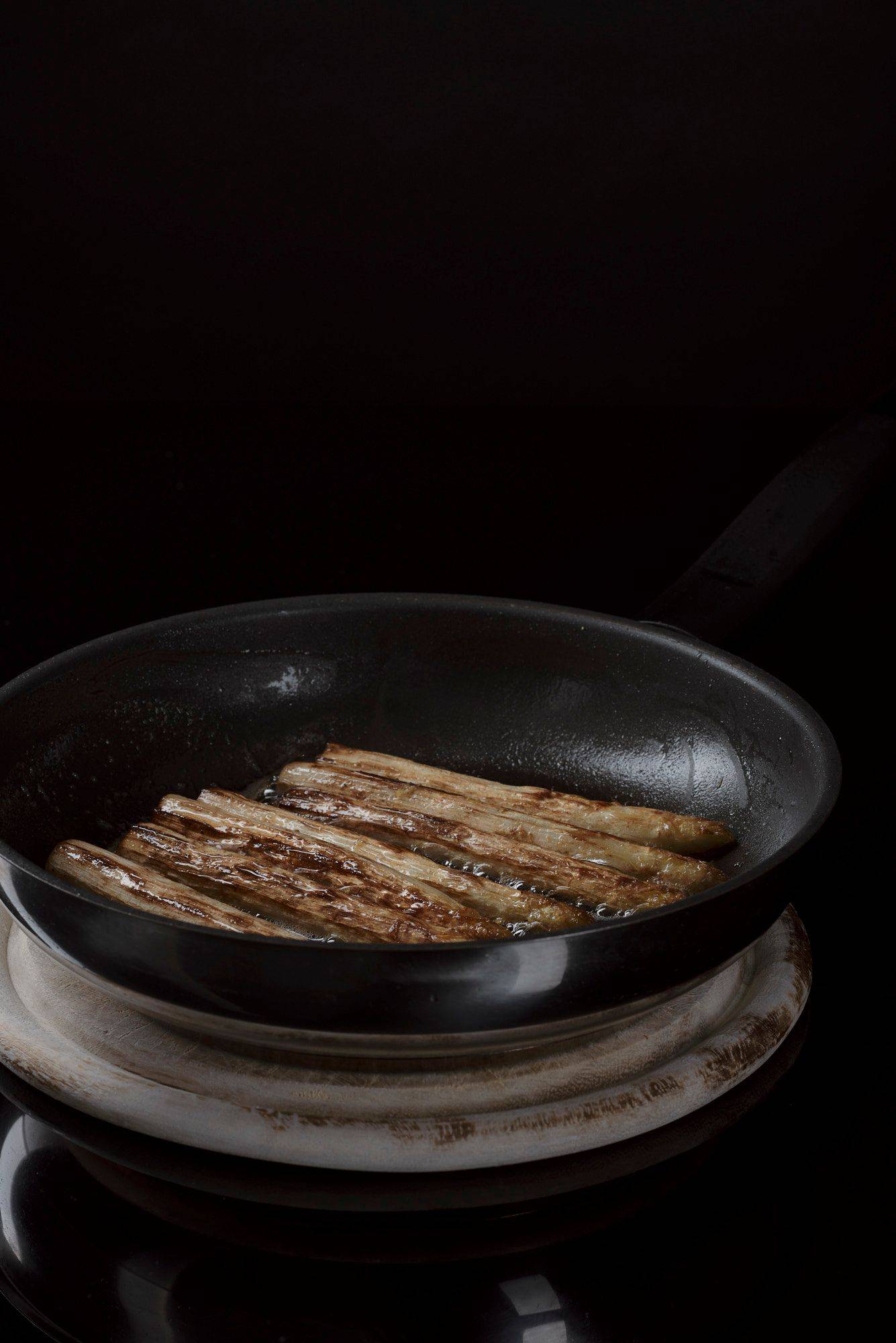roasted-asparagus roasted asparagus in a frying pan with black background