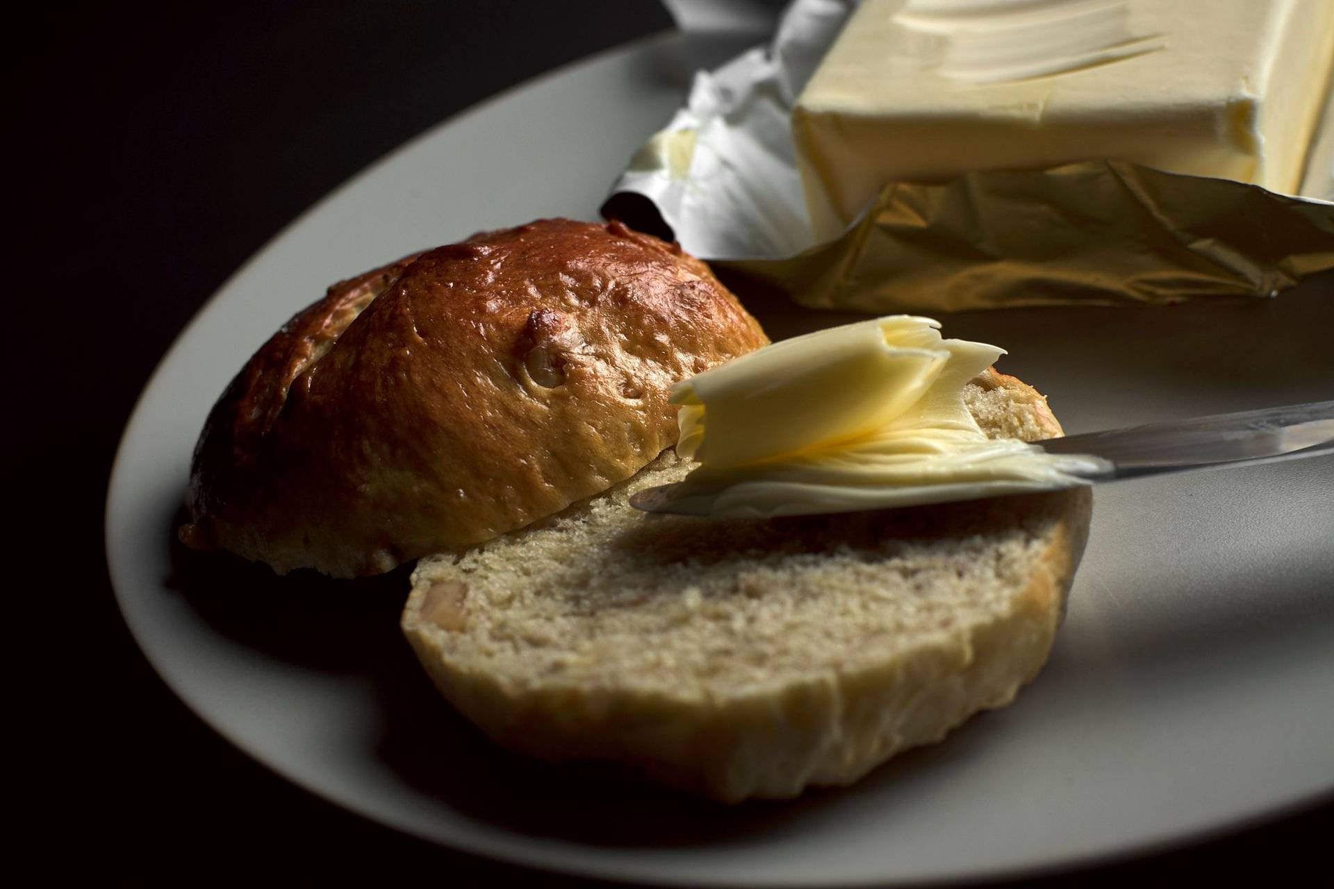 brioche-buns-with-walnuts brioche bun with walnuts on a plate with butter and black backgound