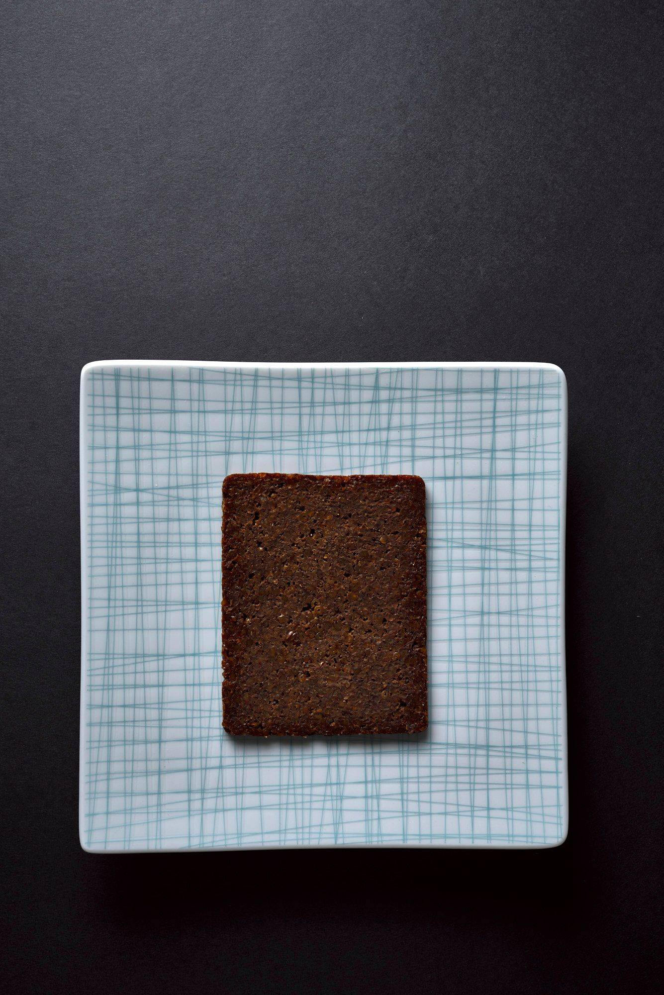 pumpernickel-bread a slice of pumpernickel bread on a plate with black background