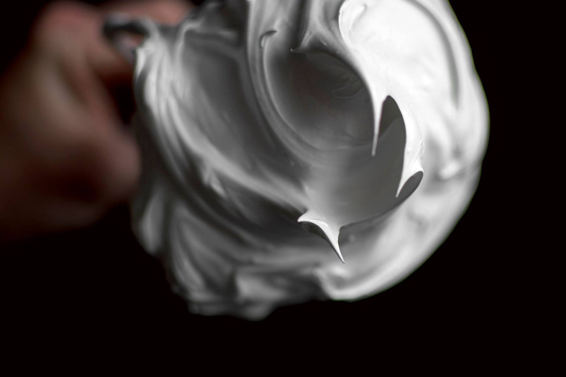 meringue creamy meringue on a whisk with black background