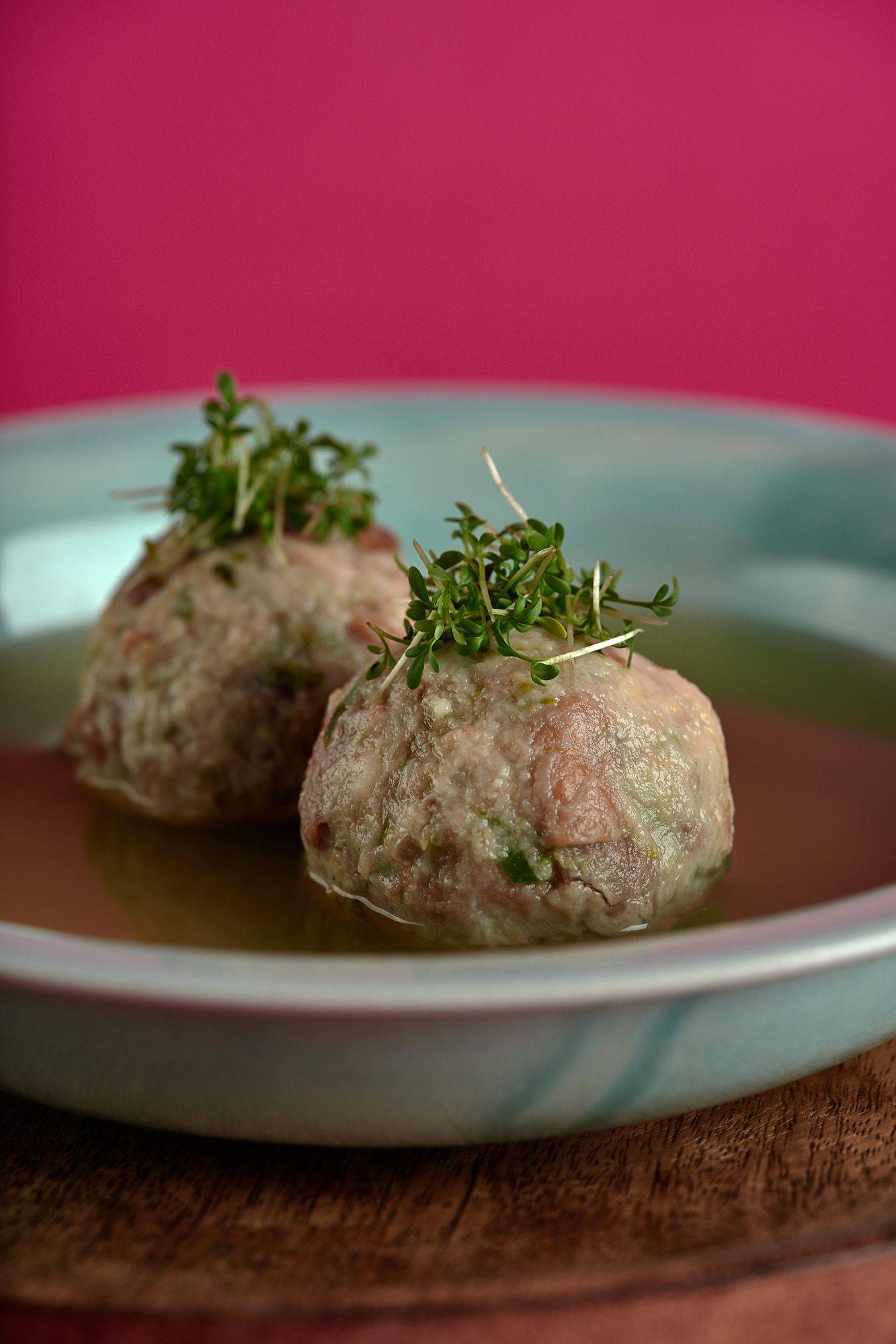 vegan-bread-dumplings-with-brussels-sprouts-and-vegetable-broth vegan bread dumplings with brussels sprouts and vegetable broth on a turquoise plate with pink background