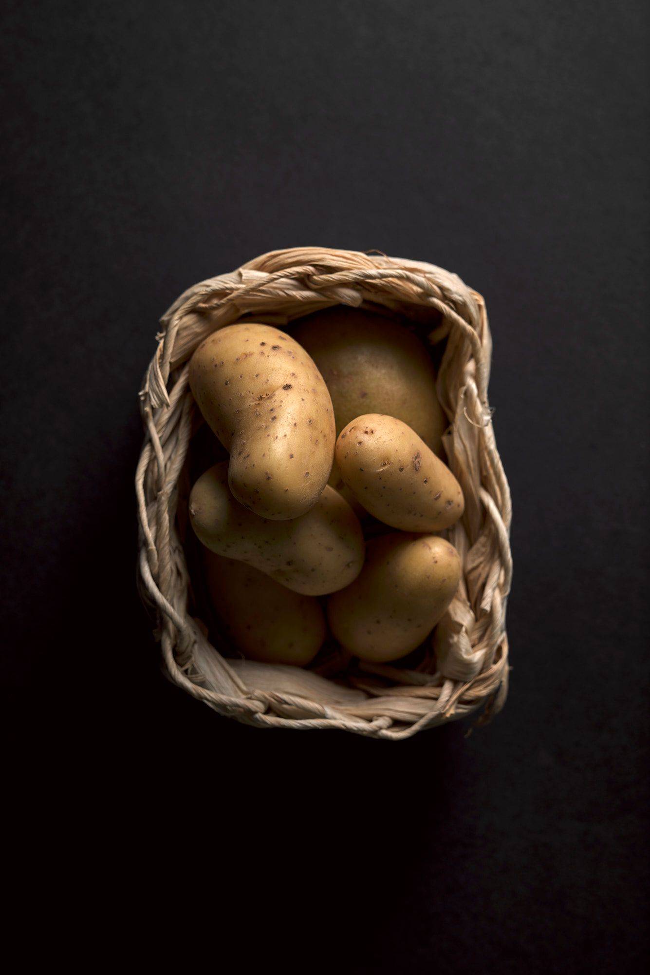 potatoes potatoes in a small basket on black background