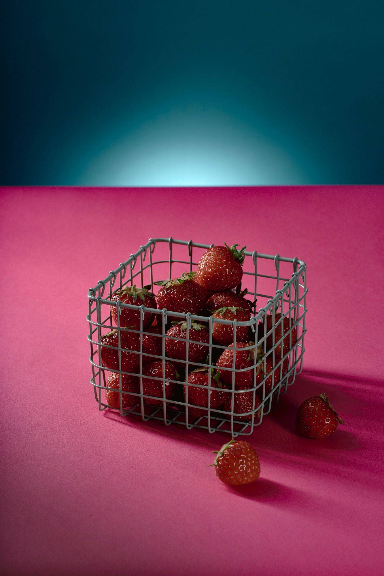 strawberries a small basket of strawberries with pink and blue background