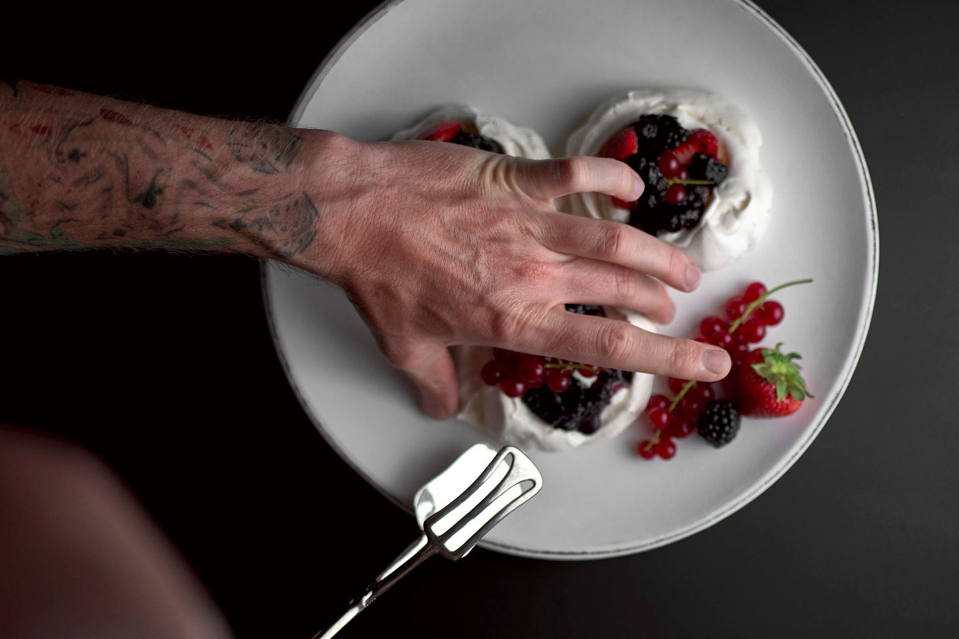 pavlova-with-berries-and-salted-cream pavlova with berries and salted cream on a white plate with black background