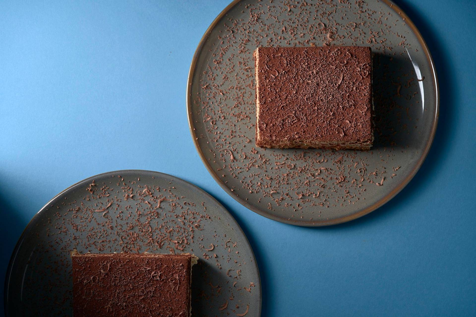 original-italienisches-tiramisu-dessert original italienisches tiramisu dessert auf grauem teller mit blauem hintergrund