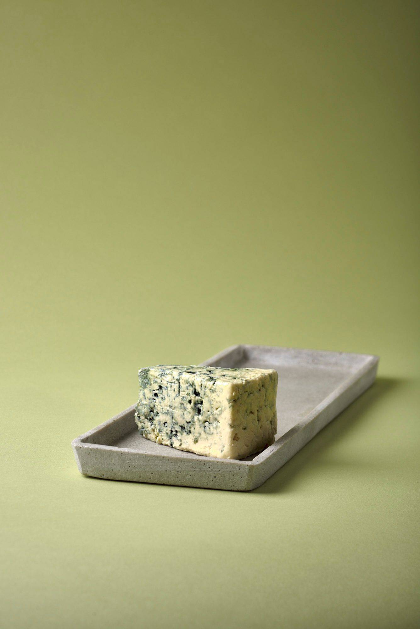 blue-cheese blue cheese on a concrete plate with green background
