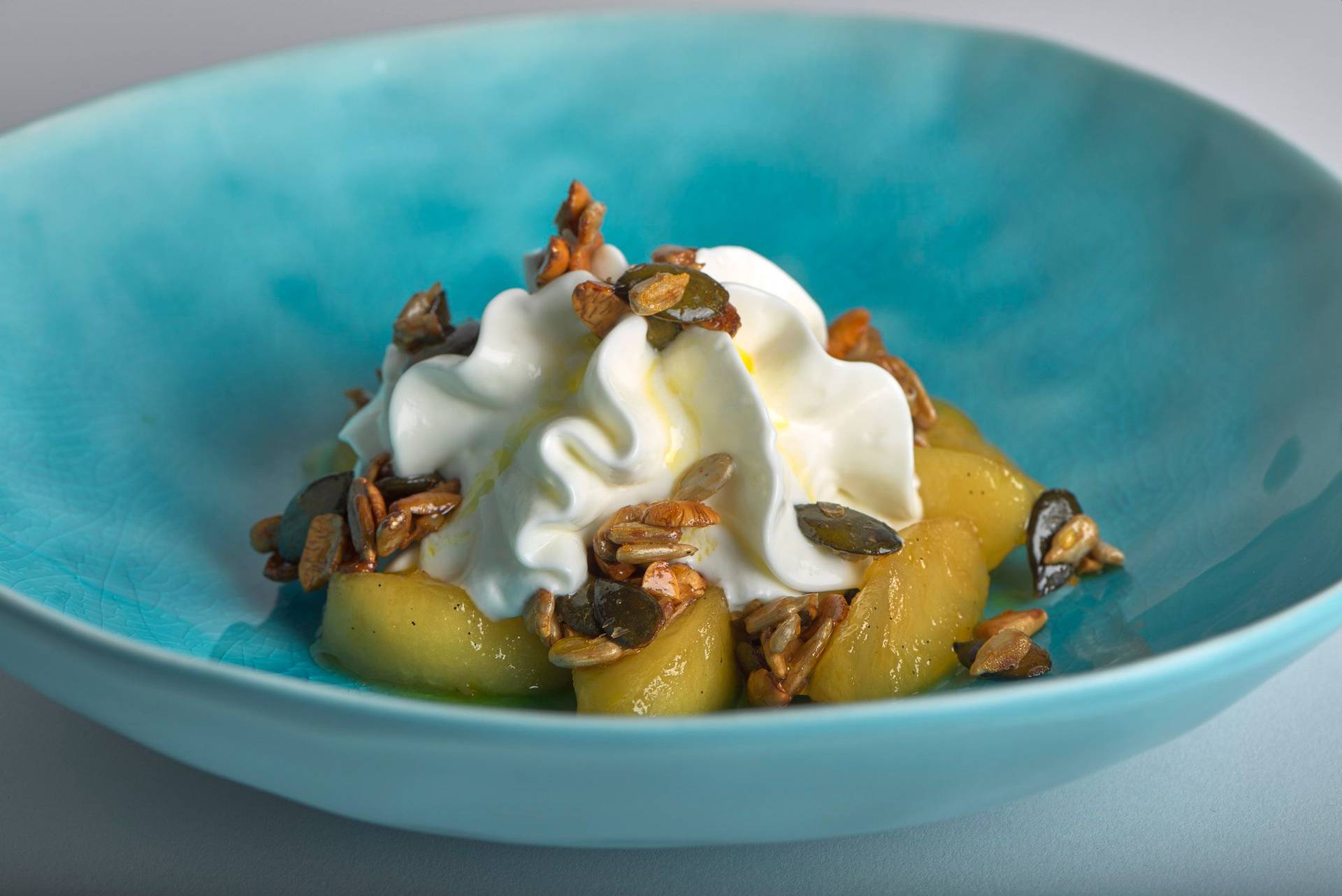 caramelized-apples-with-nuts-quark-and-linseed-oil caramelized apples with nuts quark and linseed oil on a turquoise plate with white background