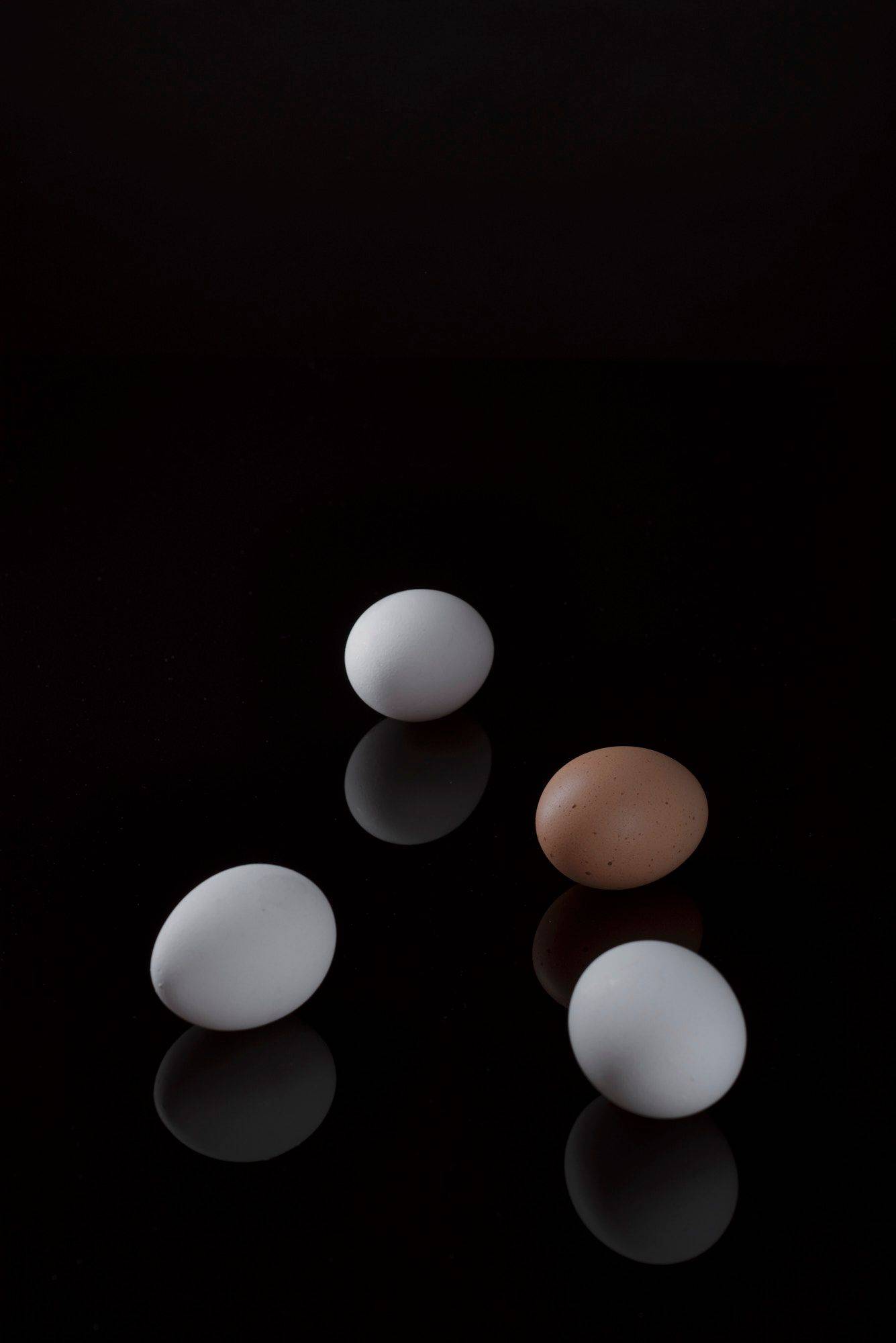 eggs three white and one brown egg with black background
