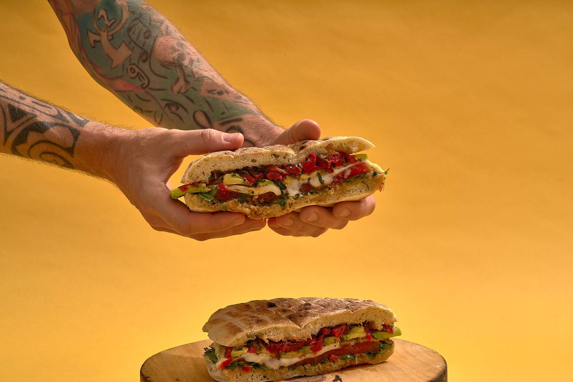 vegetarian-sandwich-with-grilled-watermelon-gremolata-garlic-paste-and-cheese hands holding vegetarian sandwich with grilled watermelon gremolata garlic paste and cheese on yellow background