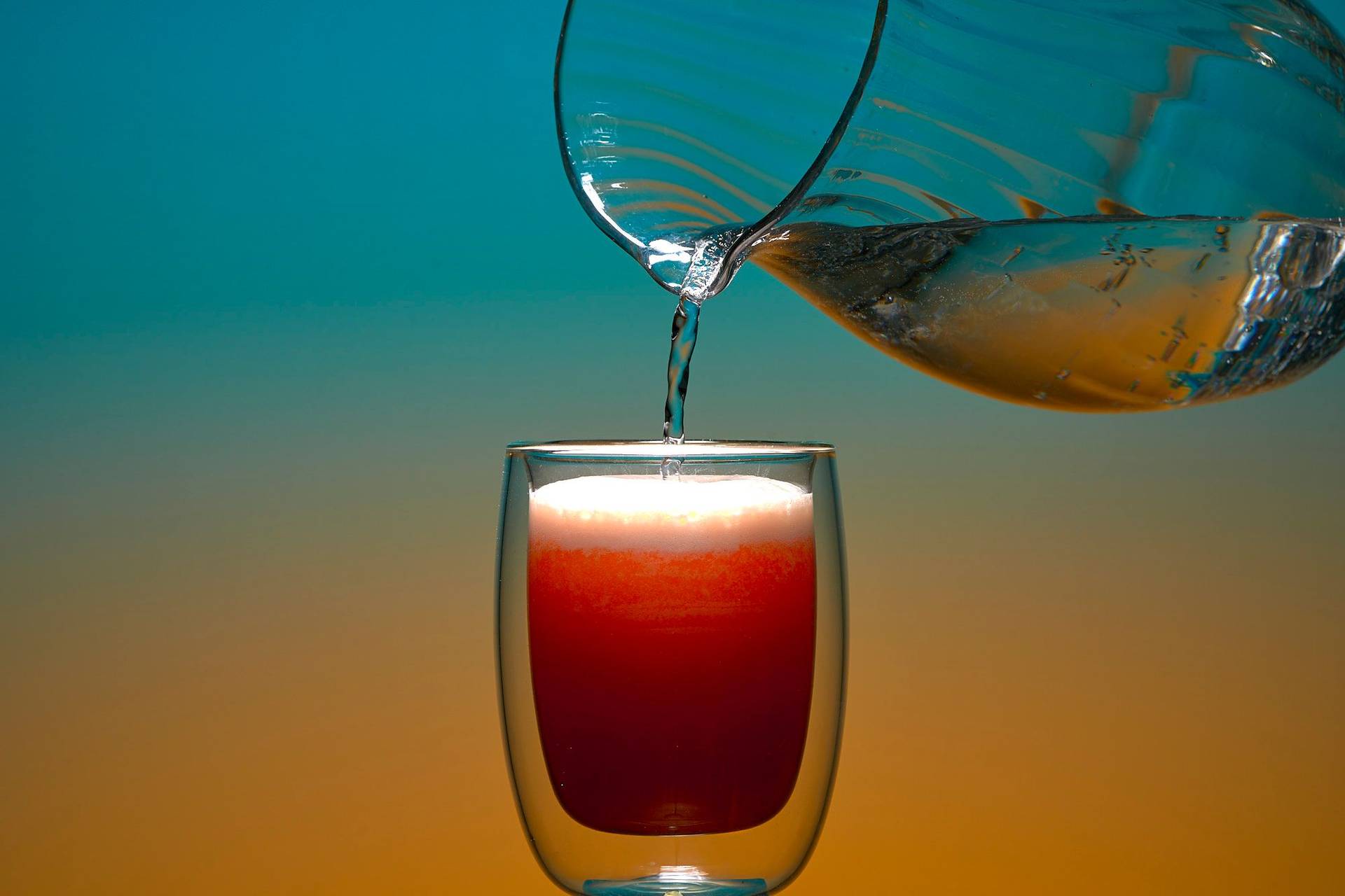 pouring-non-alcoholic-grapefruit-fizz-mocktail pouring non-alcoholic grapefruit fizz mocktail on blue and orange background