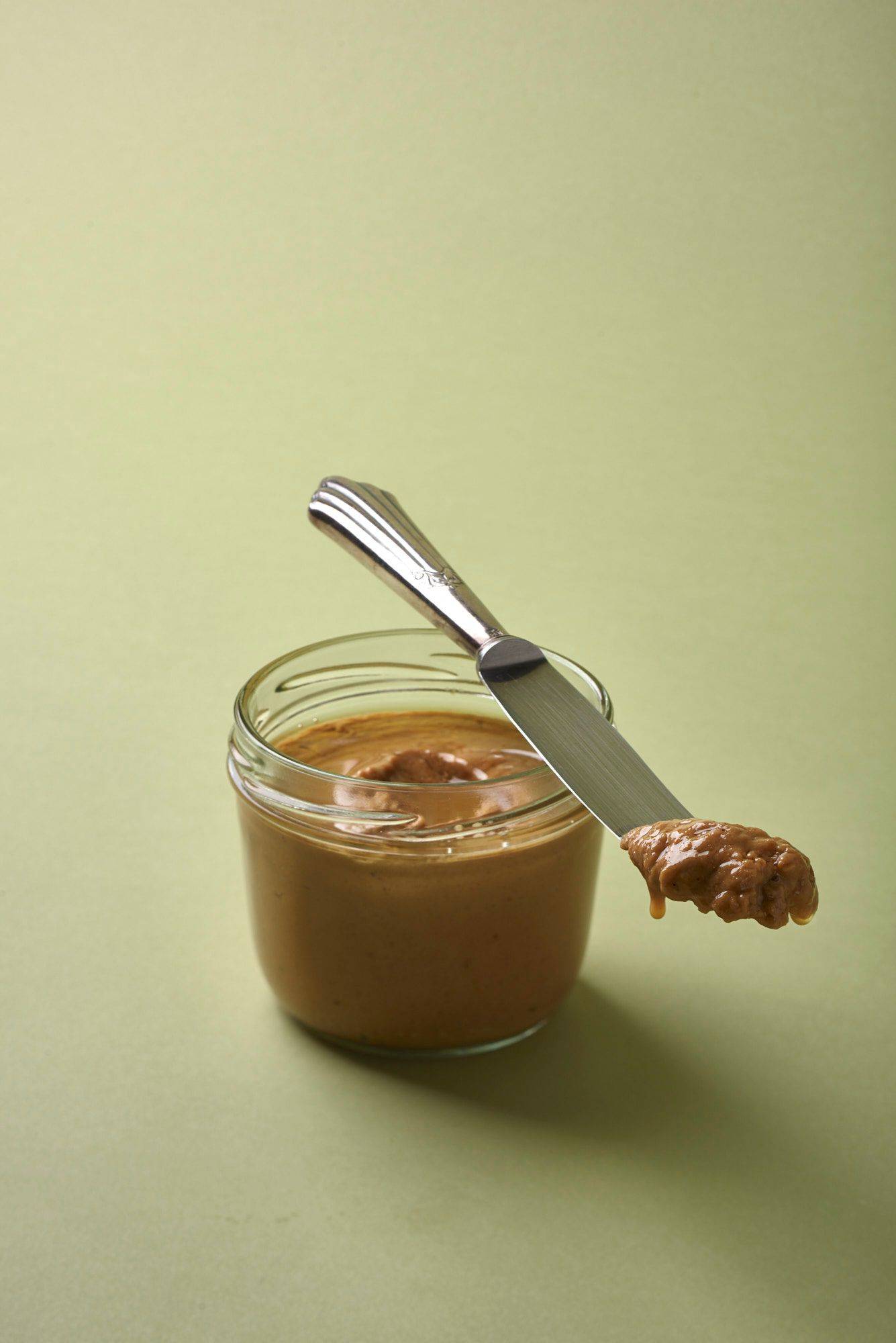 roasted-almond-butter a jar with roasted almond butter with green background