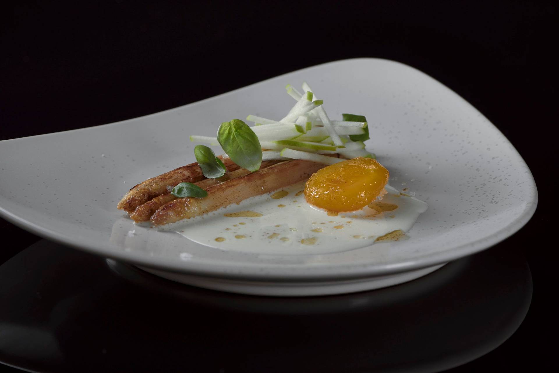 roasted-white-asparagus-with-cured-egg-yolk-basil-and-green-apple roasted white asparagus with cured egg yolk basil and green apple on a beige plate with black background
